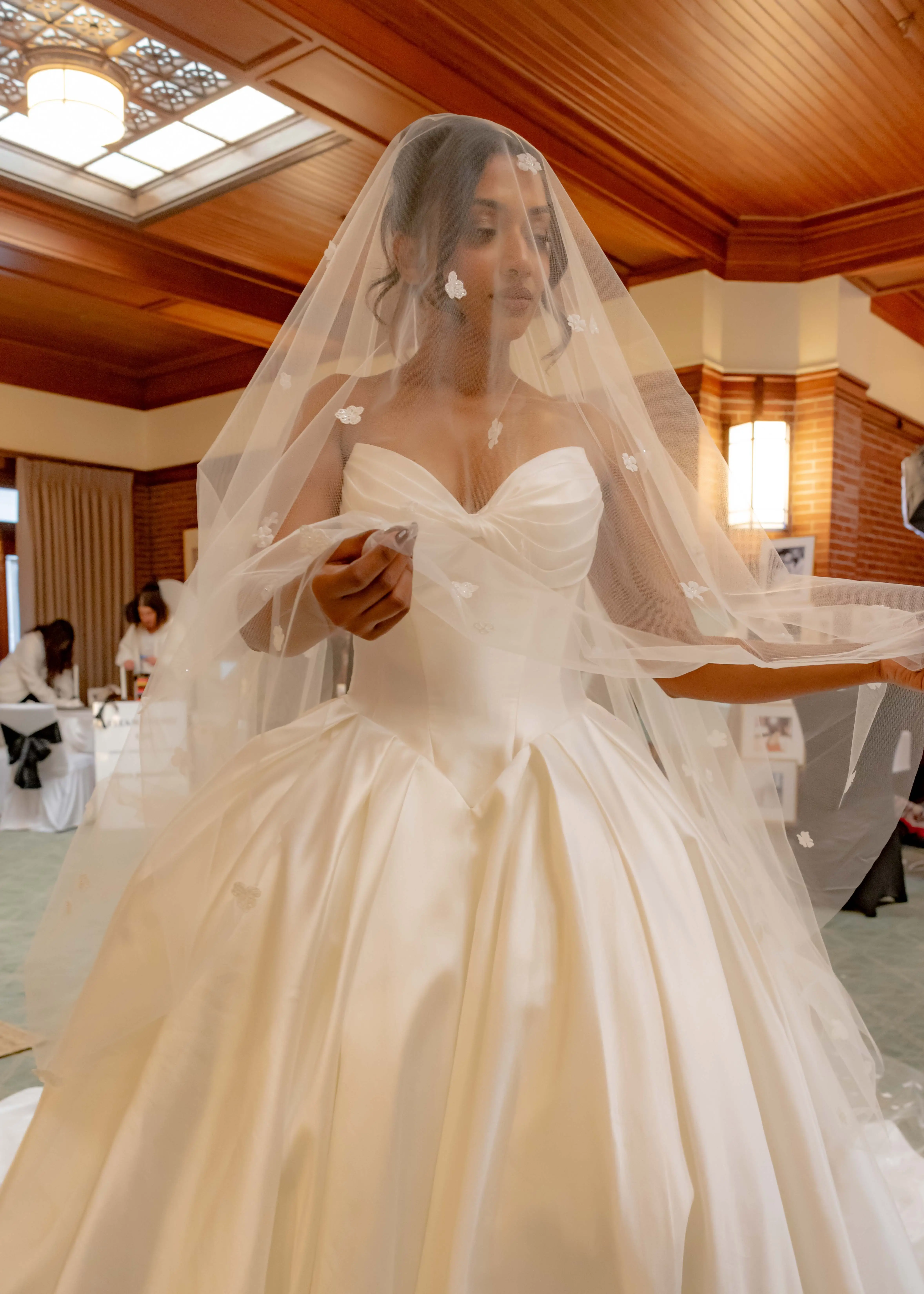 A woman in a basque wedding dress and a floral veil.
