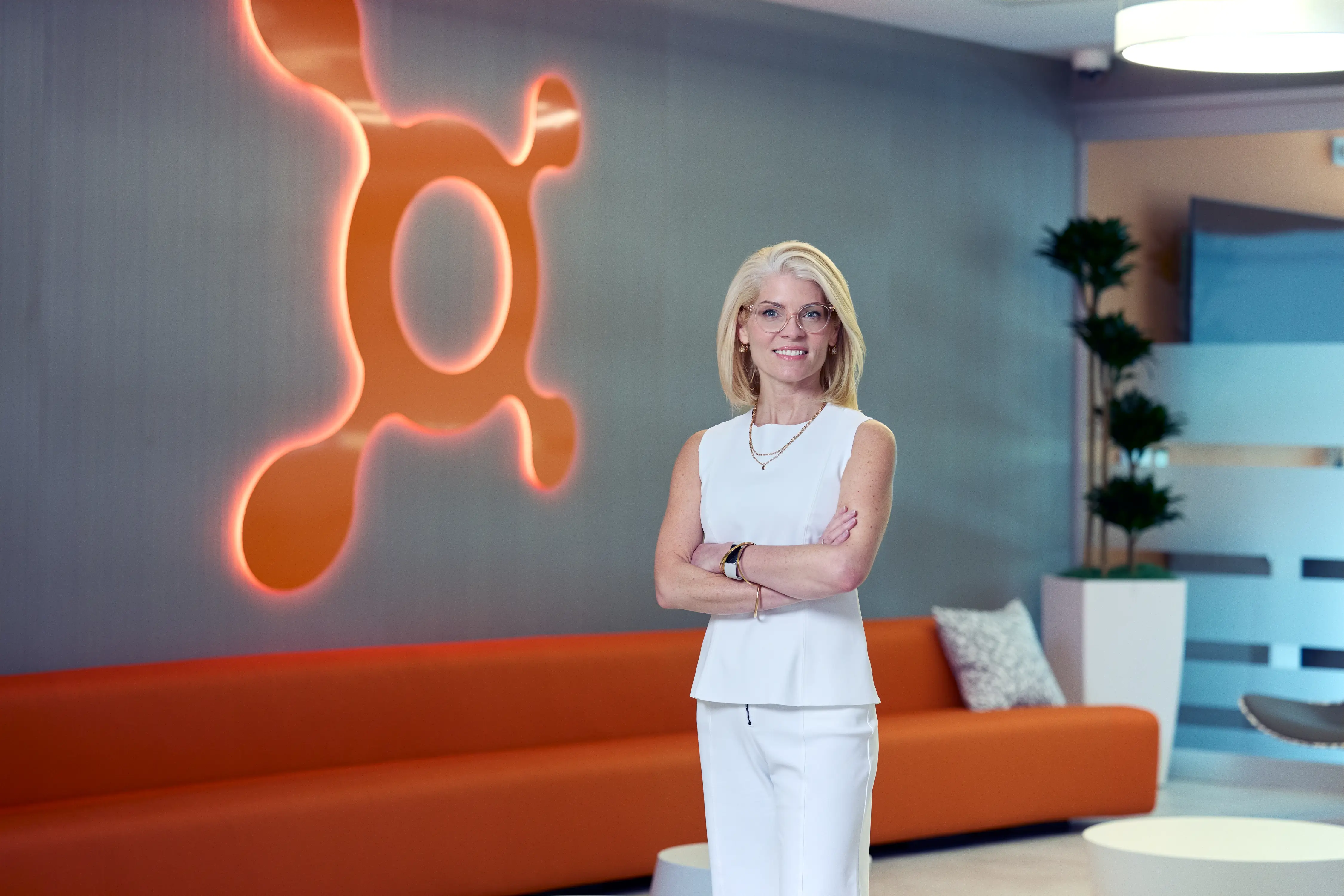 Orangetheory president Lauren Cody standing in an office with the brand's logo on the wall behind her