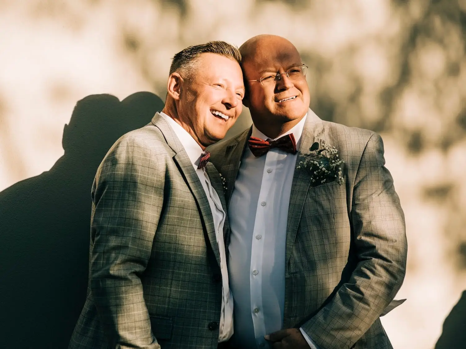 Two grooms lean together and smile on their wedding day.