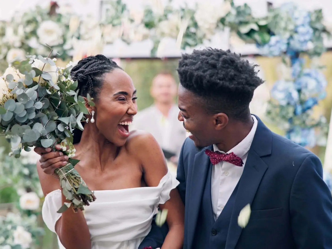 A bride and groom leave their wedding ceremony, smiling at each other.