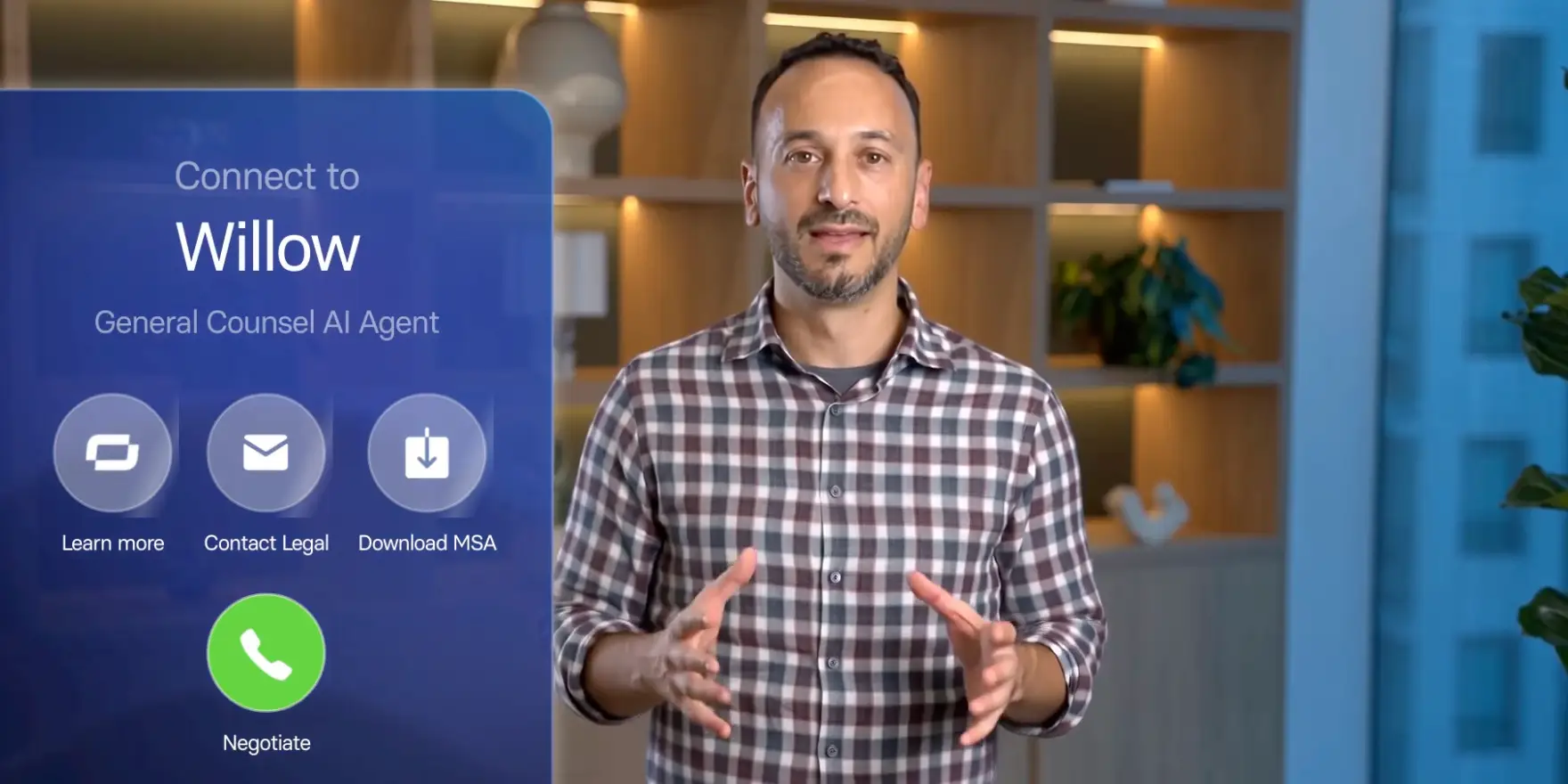 A man gestures while standing beside a screen advertising Willow, a general counsel AI agent with options to learn more, contact legal, download an MSA, or negotiate.