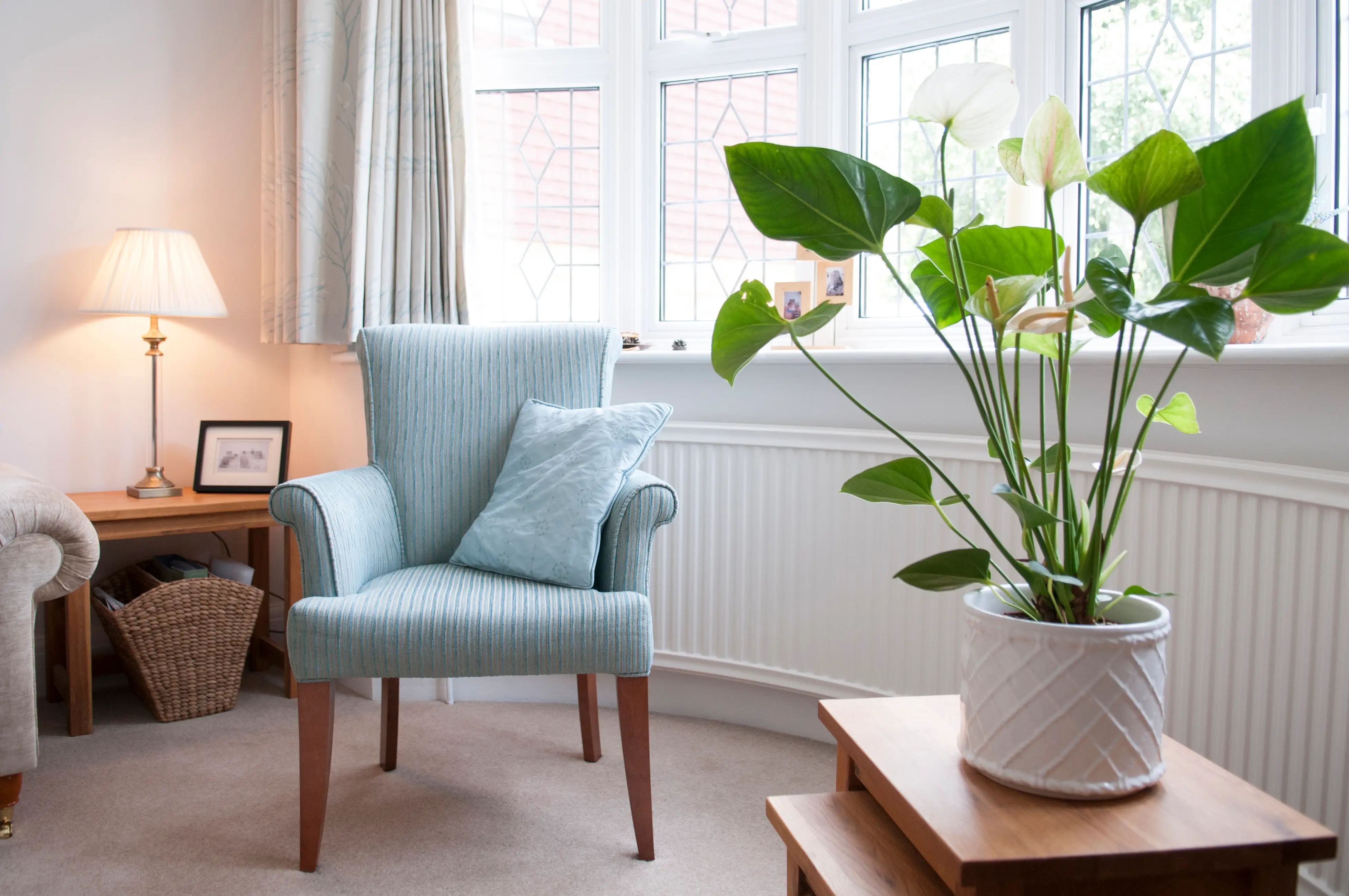 light blue free standing accent armchair with armrests a potted plant sitting on a nest of tables