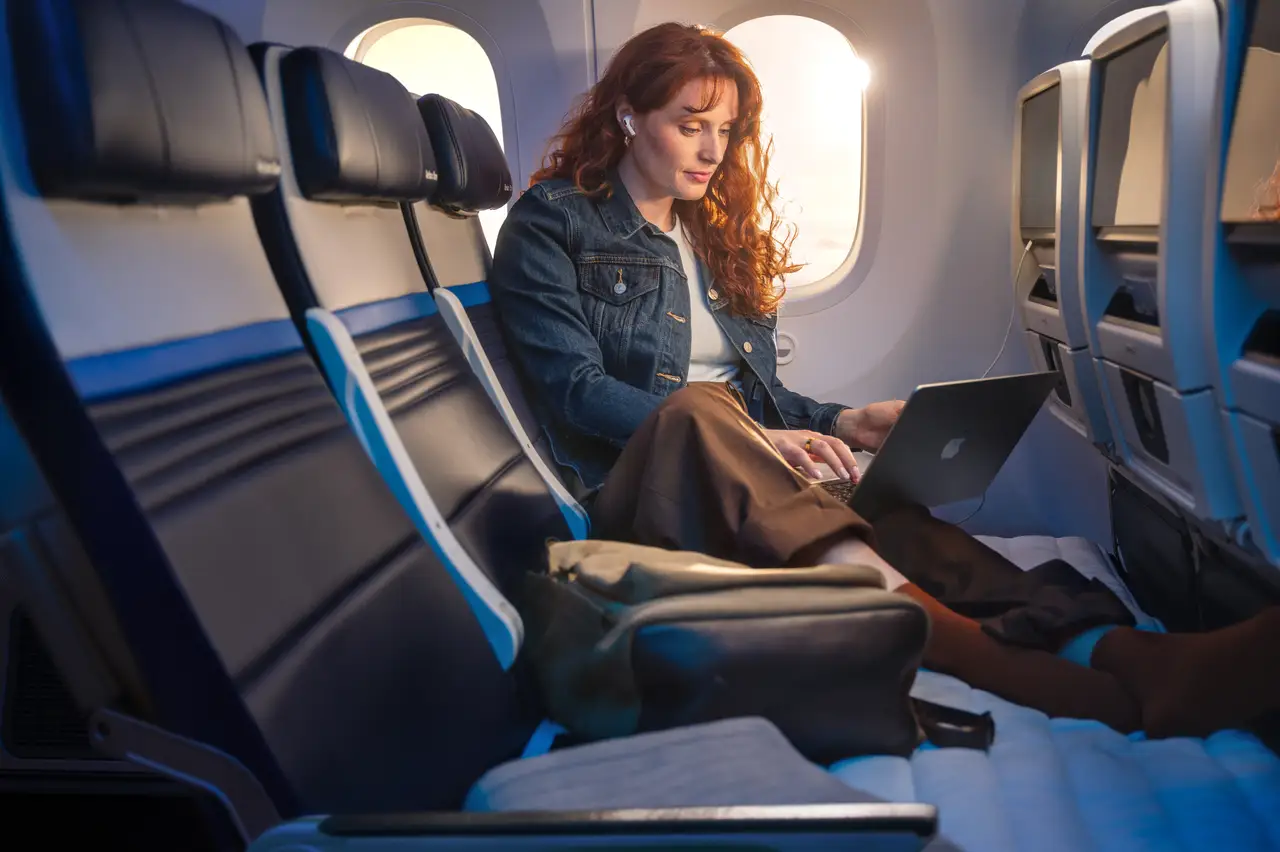 A rendering of a red headed woman stretched out on the Relax Row with her laptop.
