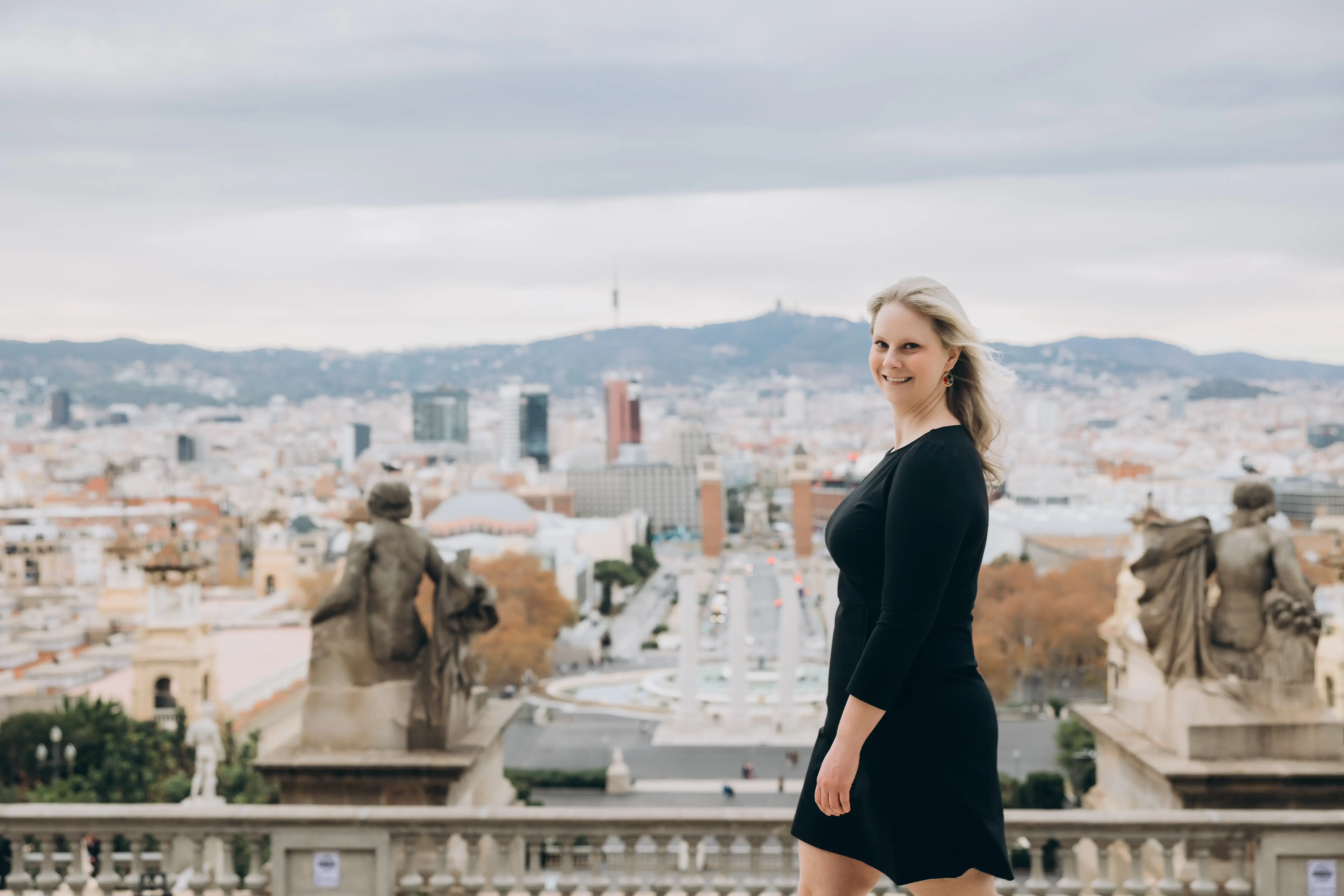 An American woman posing with the Barcelona skyline.