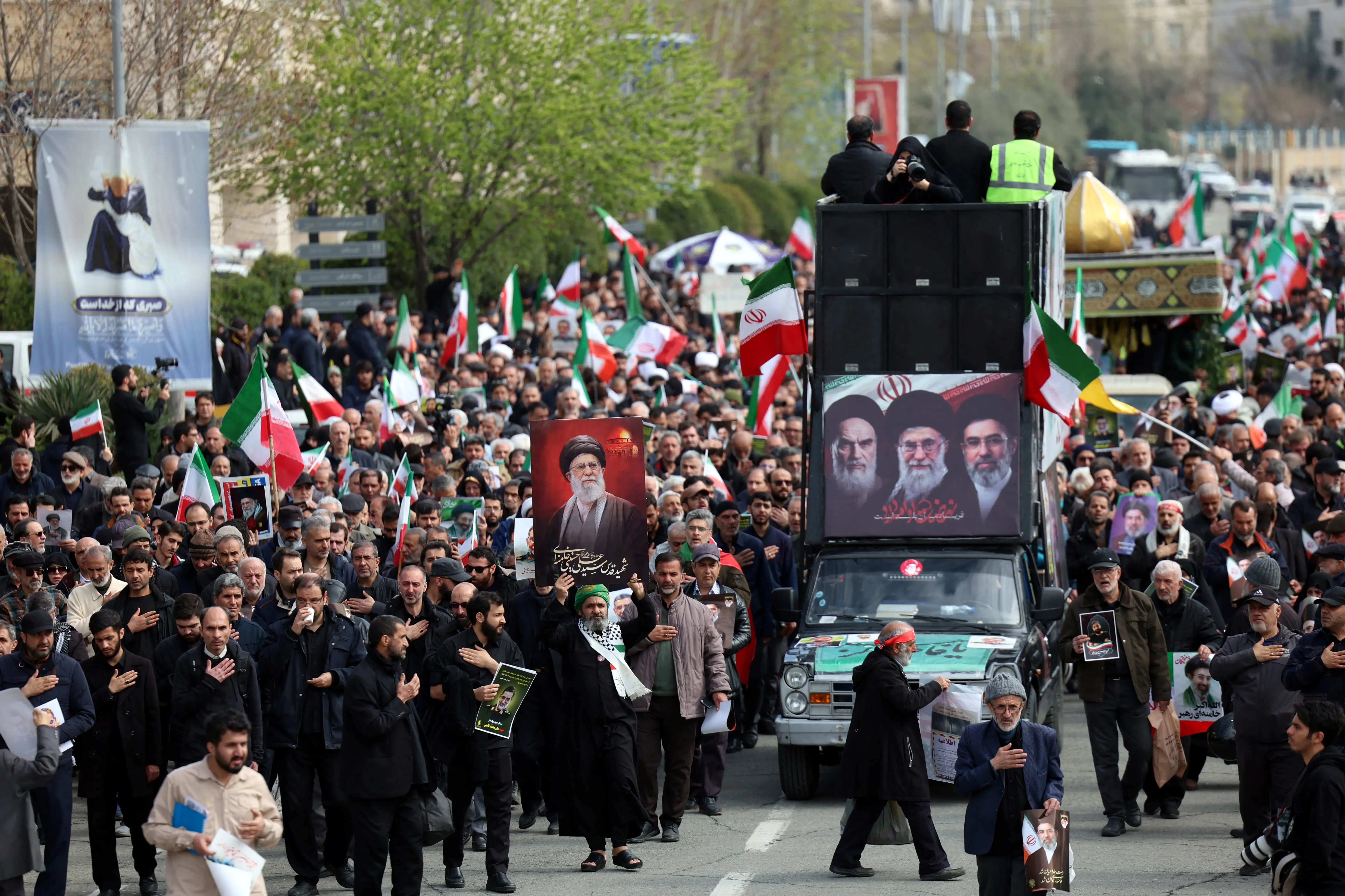 A caravan in Iran passes funeral attendees