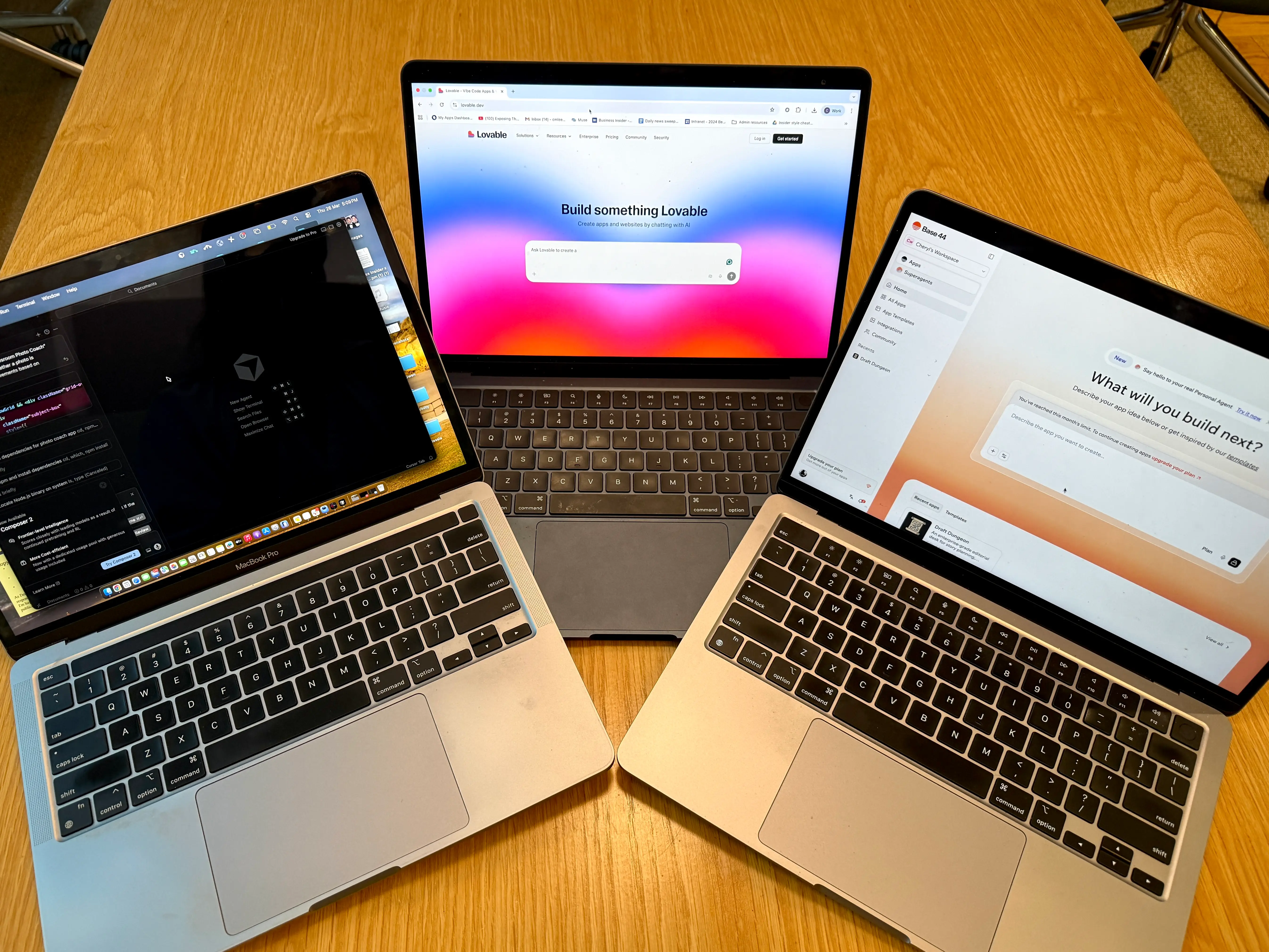 Three laptops with different vibe coding platforms on them.