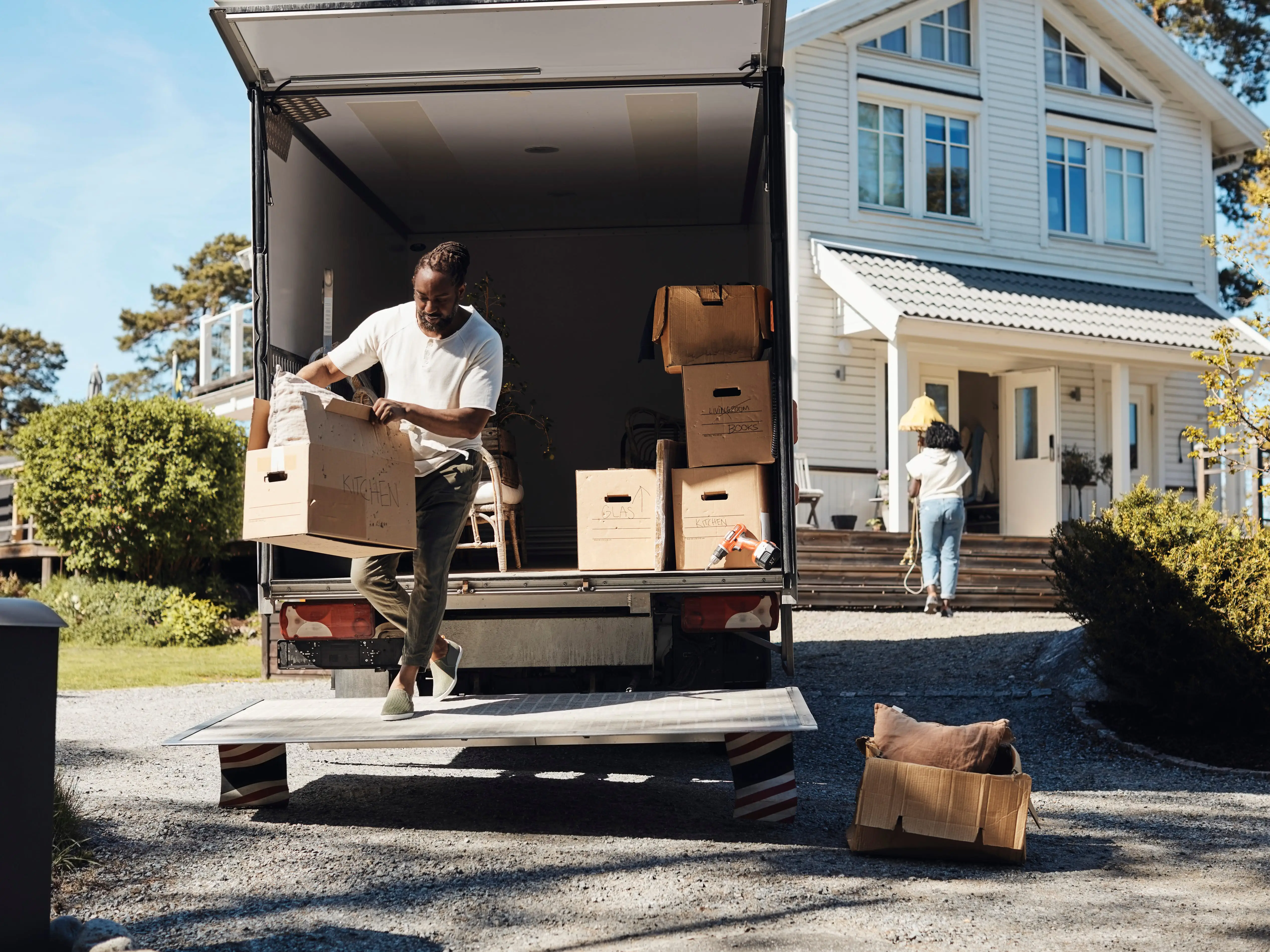 A person holding a box from a truck that has more boxes inside
