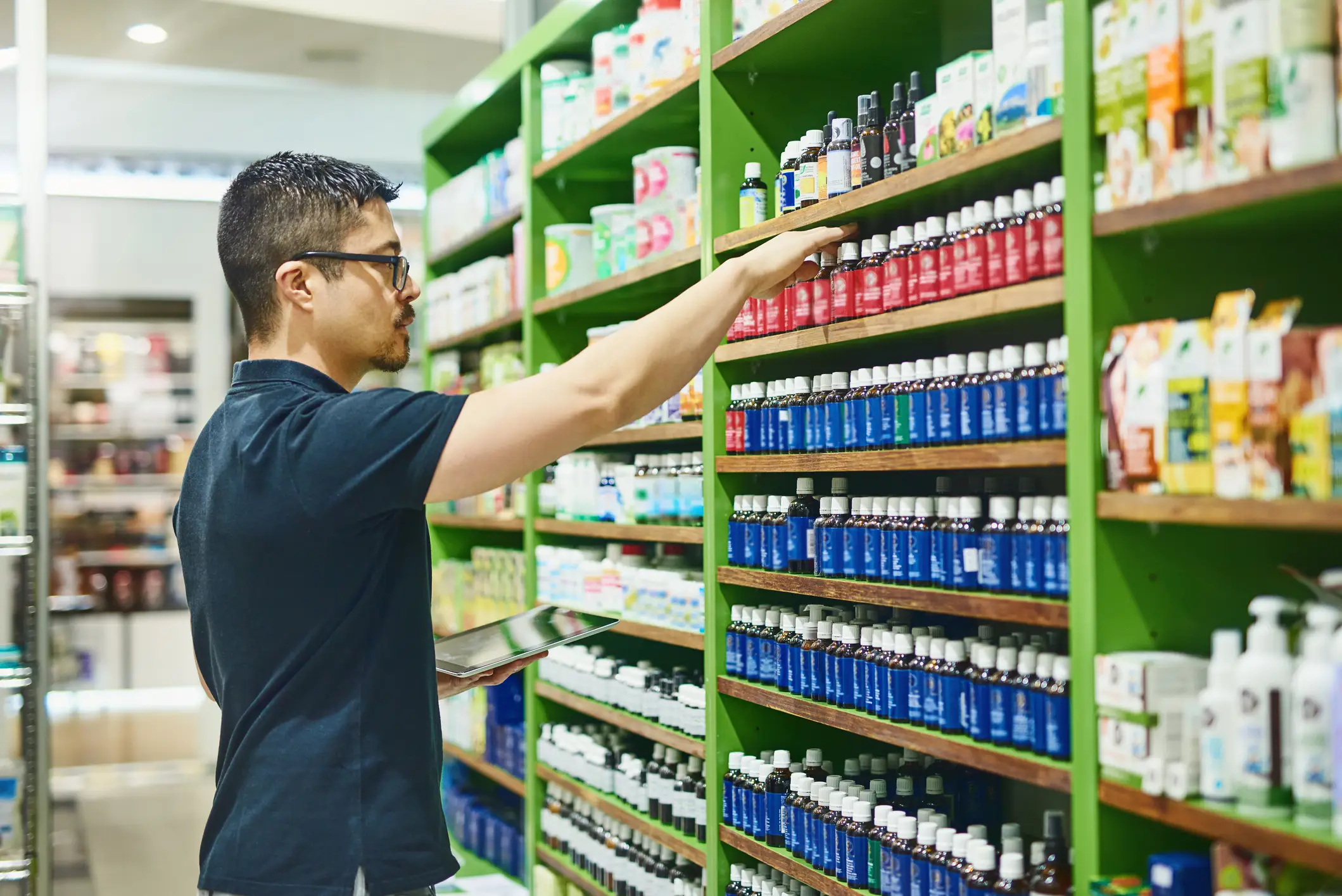 A man shopping for supplements in a store aisle.