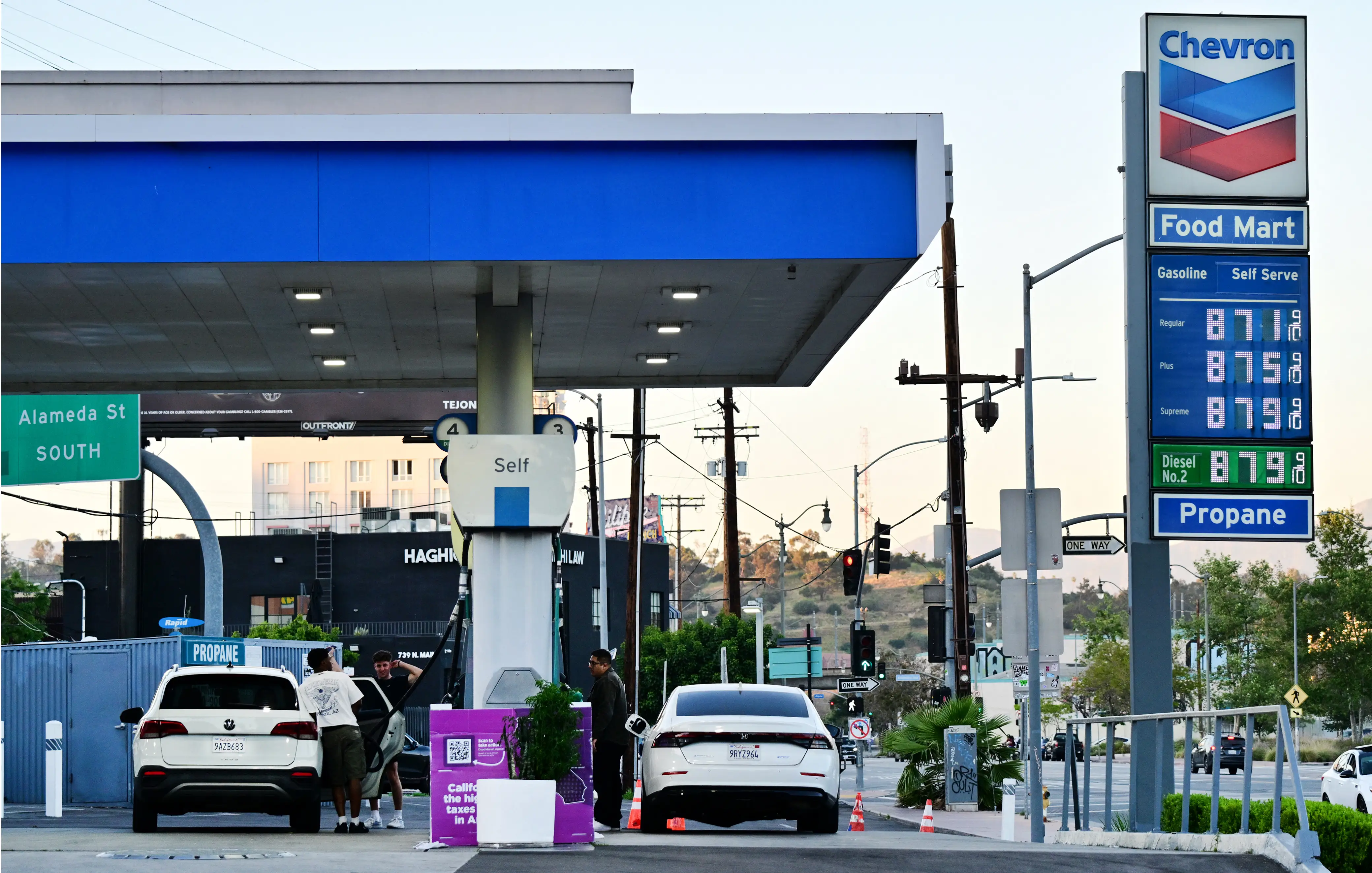 The sign of a Chevron gas station displays current prices as drivers pump gas in Rosemead, near Los Angeles, California,