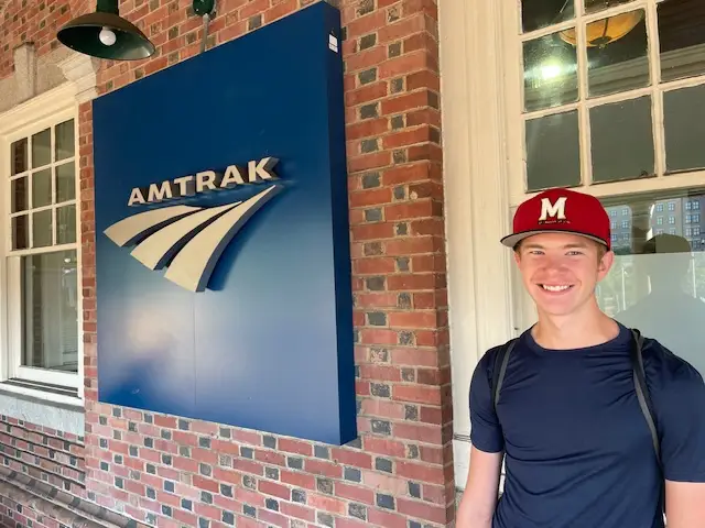 Sara Clarke's son in front of an Amtrak sign