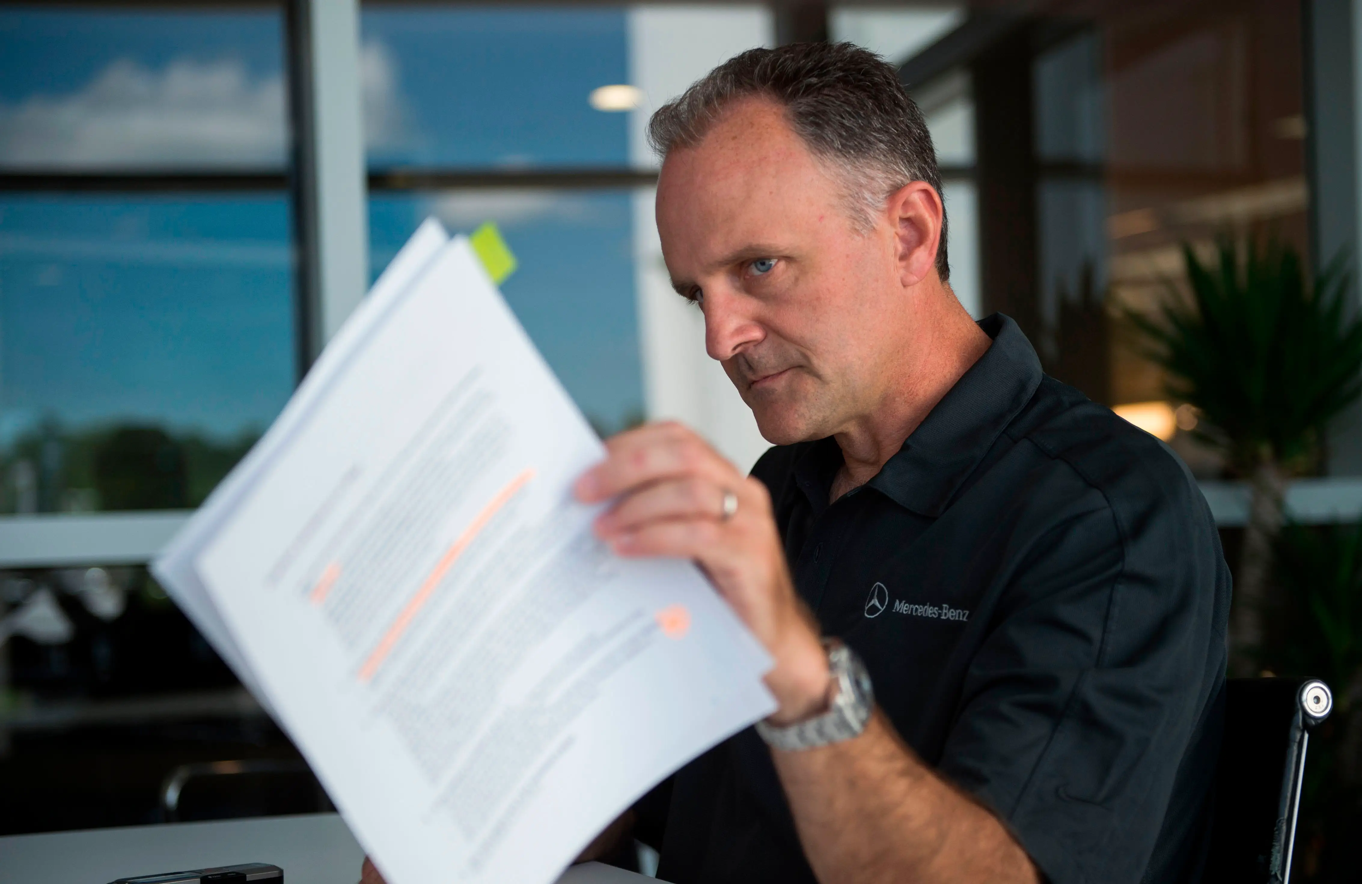 Jason Hoff, the CEO of Mercedes North America, is holding a pamphlet of highlighted papers in his left hand.