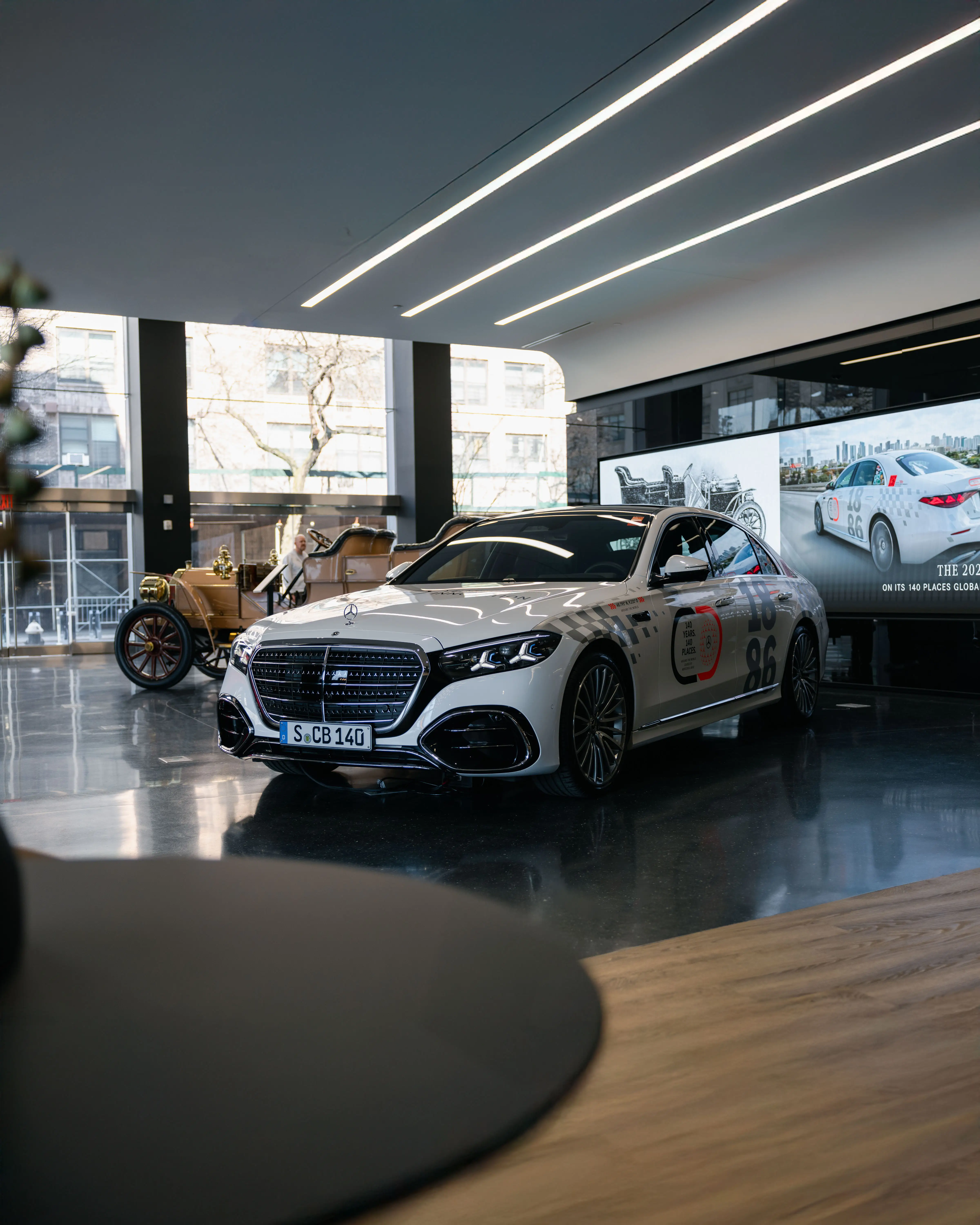 A white Mercedes S-Class with colorful decals inside a Manhattan showroom.