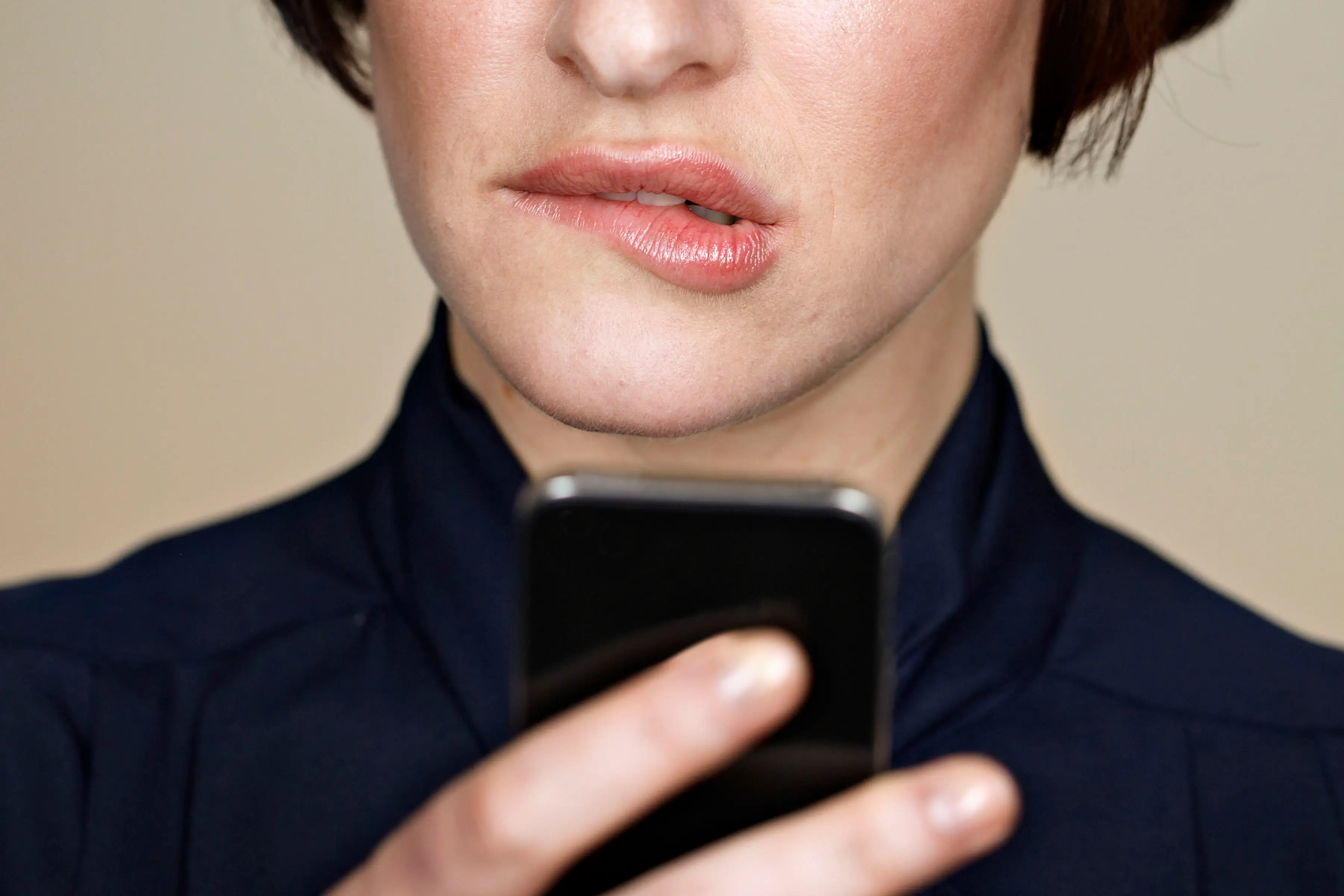 Person stares at their phone while biting their lip