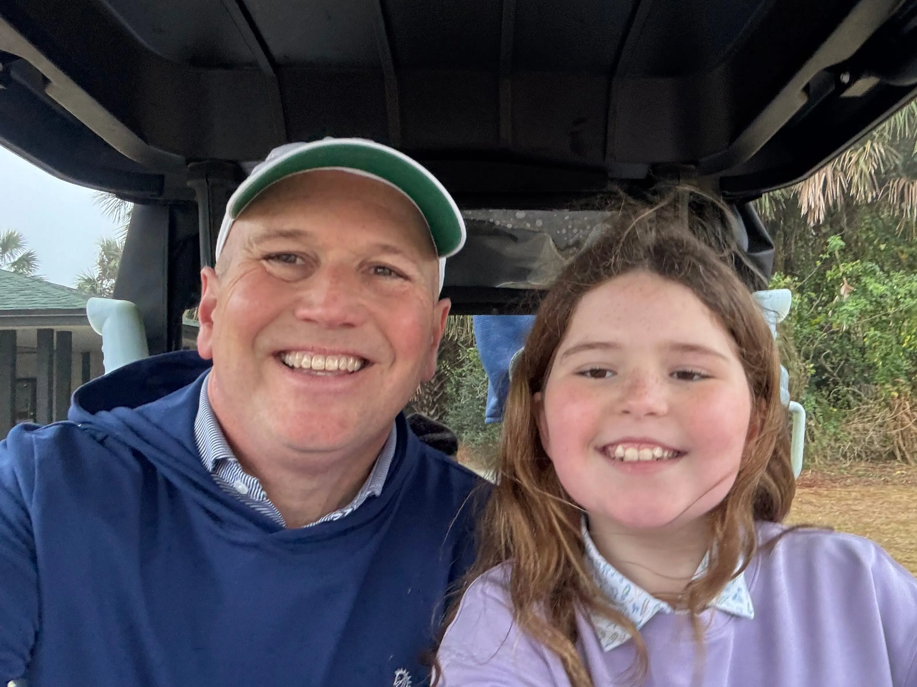Father and daughter inside a golf cart