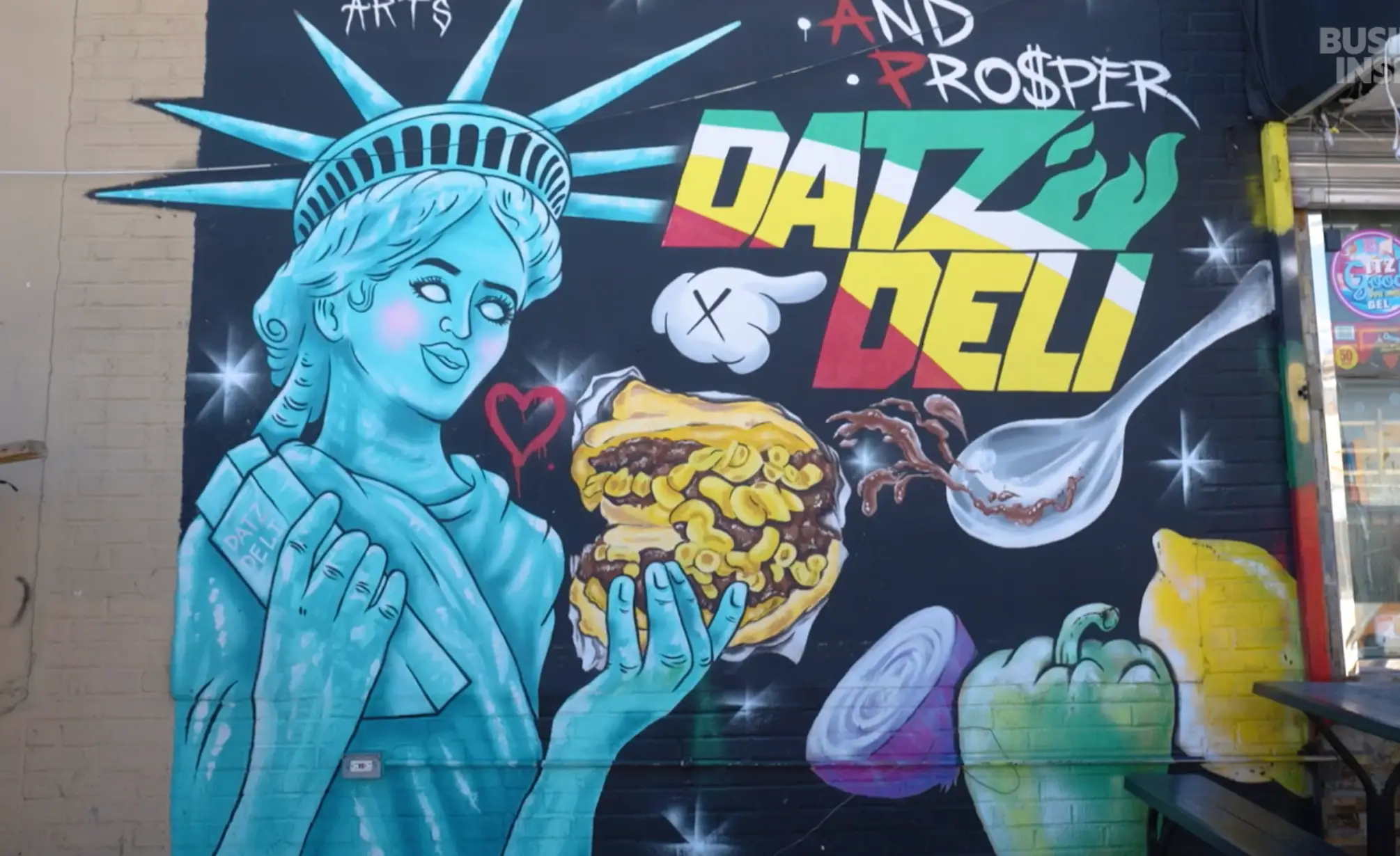 Colorful mural on the side of Datz Deli showing the statue of liberty holding a mac patty.