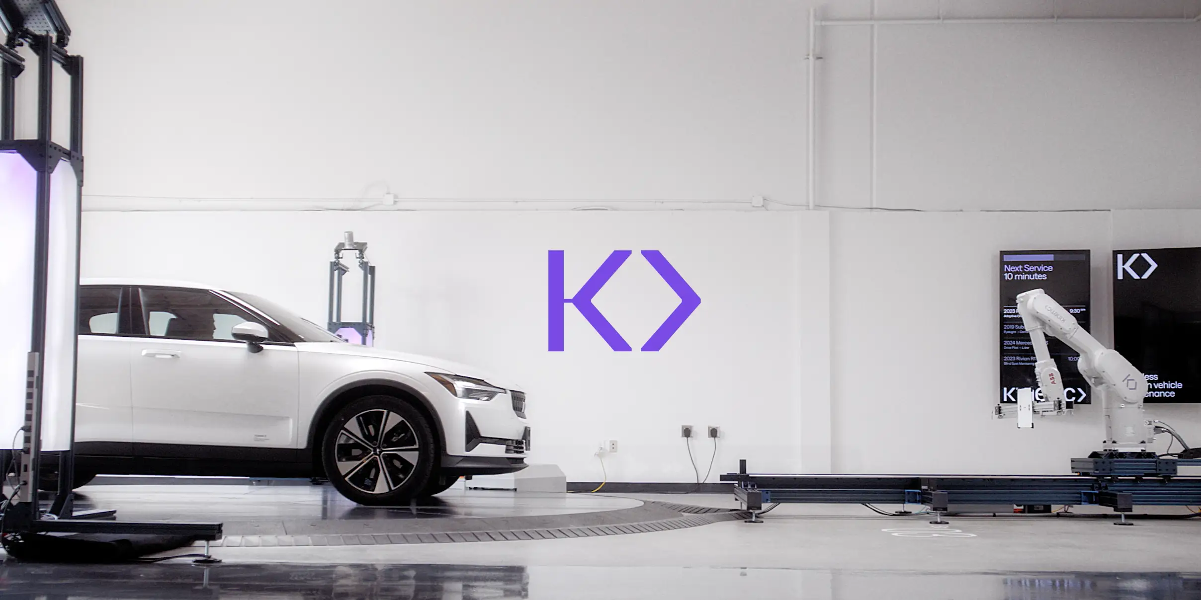 A car parked in front of a robotic arm.