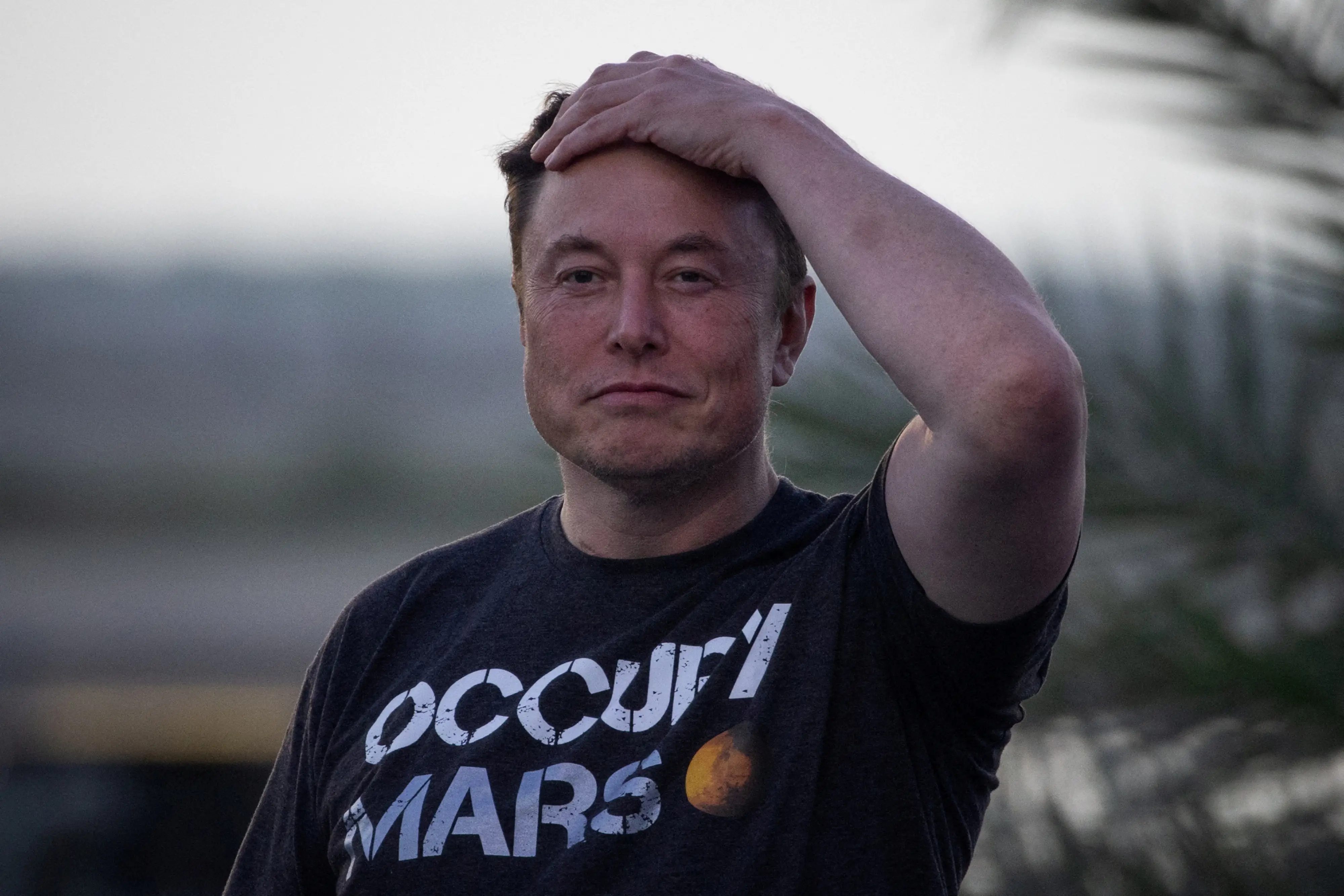 Elon Musk with his hand on his head