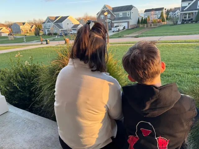 The author sits on a front step of her house with one of her sons.