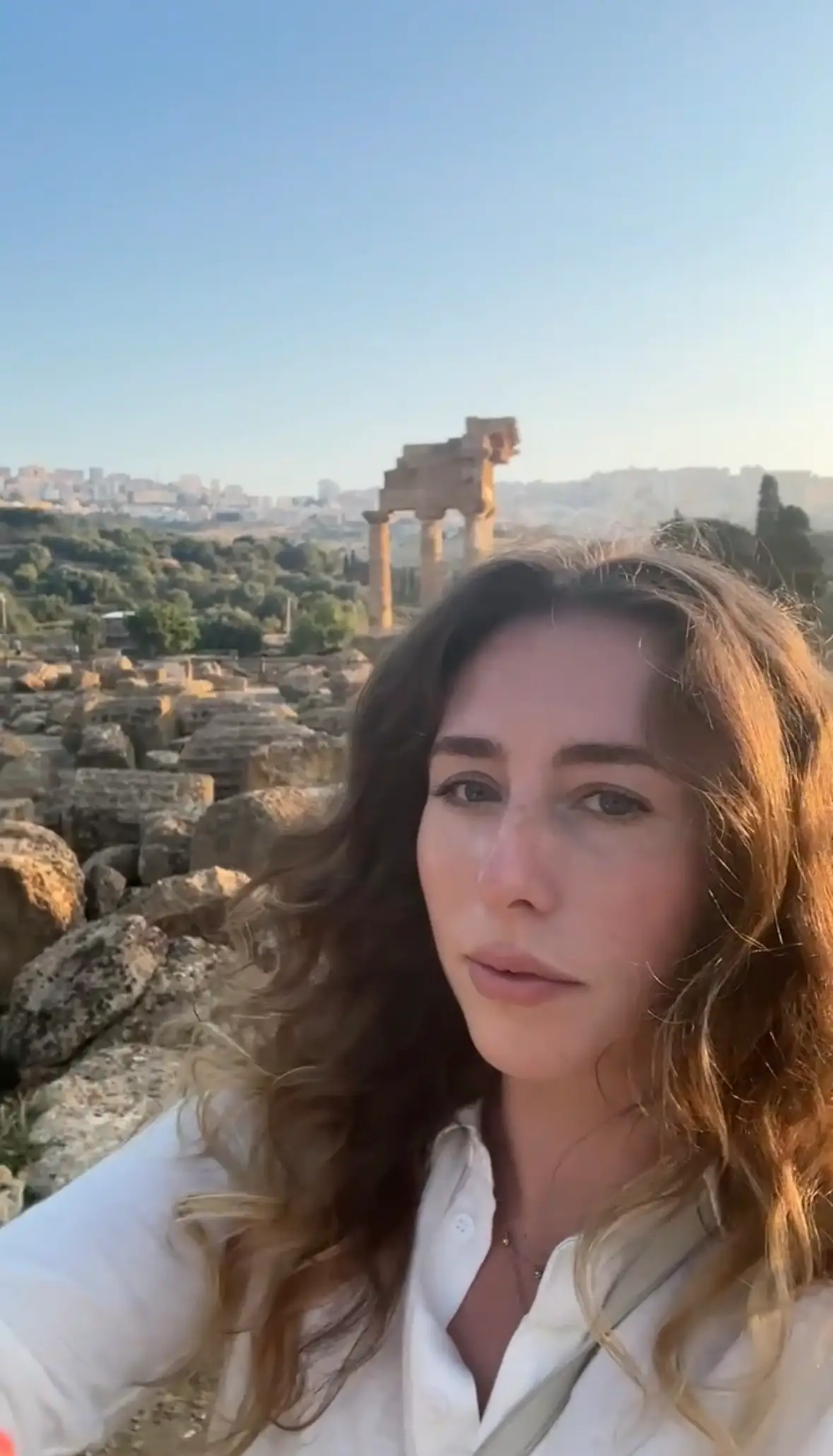 A woman taking a selfie in front of ruins in Italy.