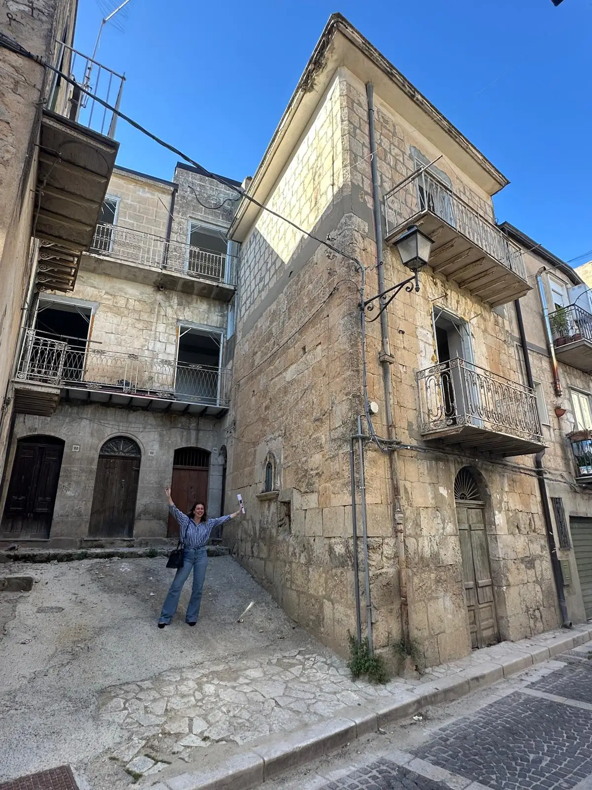 A woman standing outside a home in Italy holding a deed.