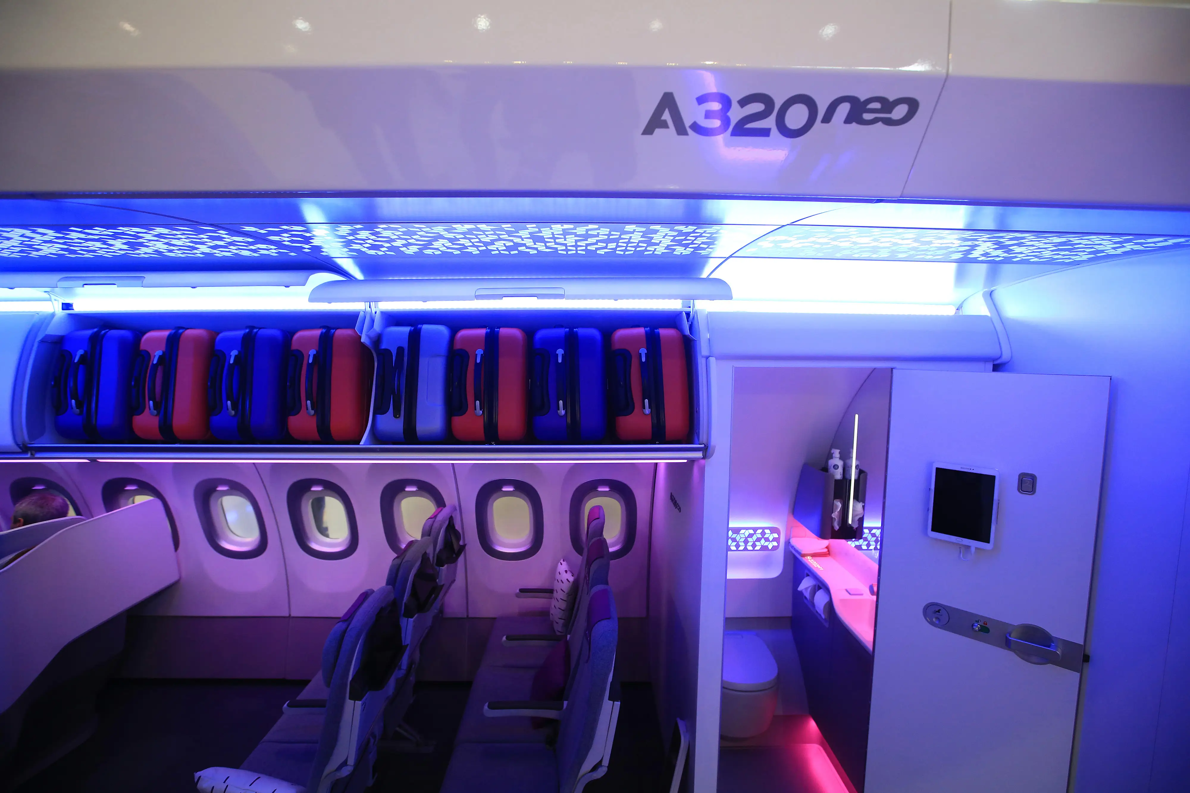Luggage sits inside Airspace XL overhead cabin storage compartments as a restroom door stands open inside a new Airbus SE A320neo cabin at the Aircraft Interiors Expo in Hamburg, Germany.