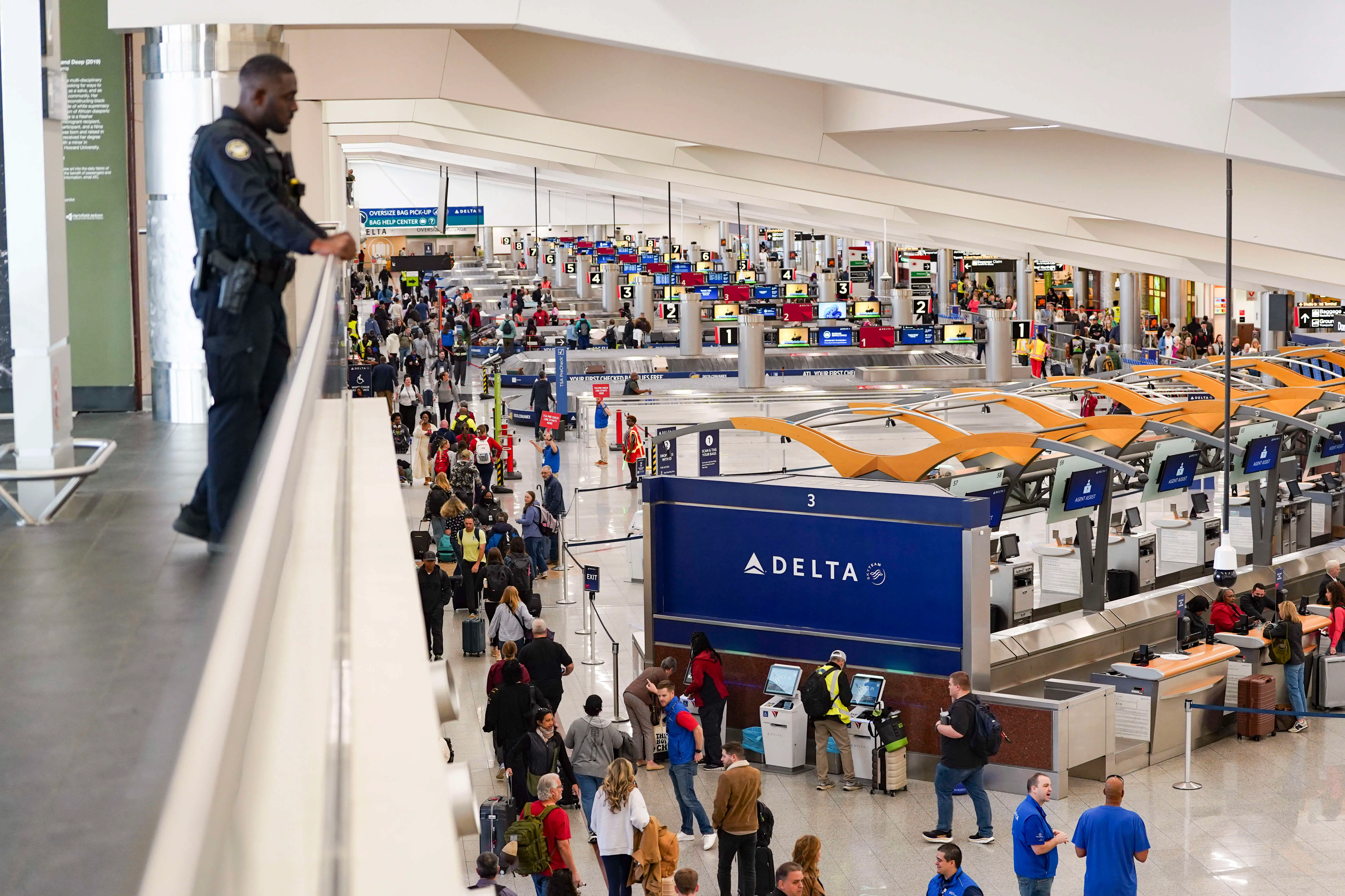 An Atlanta Police Department Officer looks on as travelers wait in long lines at Atlanta Hartsfield-Jackson International Airport on March 26, 2026 in Atlanta, Georgia
