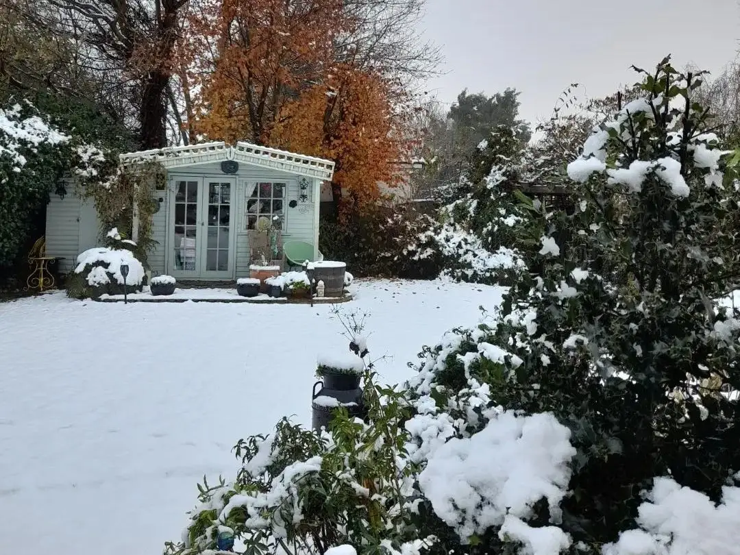 A garden shed covered in snow.