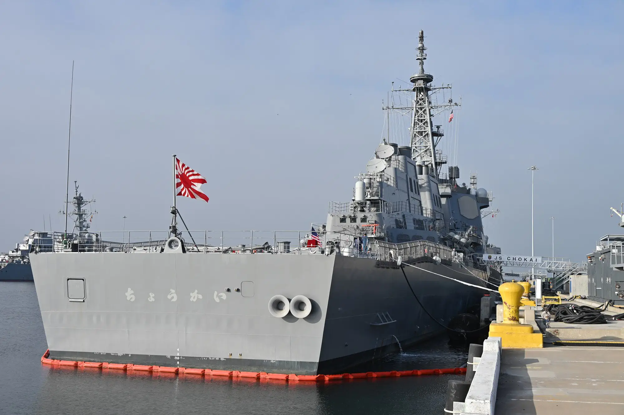 A large, grey, Japanese warship sits at a dock.