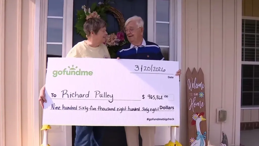 Richard Pulley and a woman hold up a giant GoFundMe check for $965,868.00.