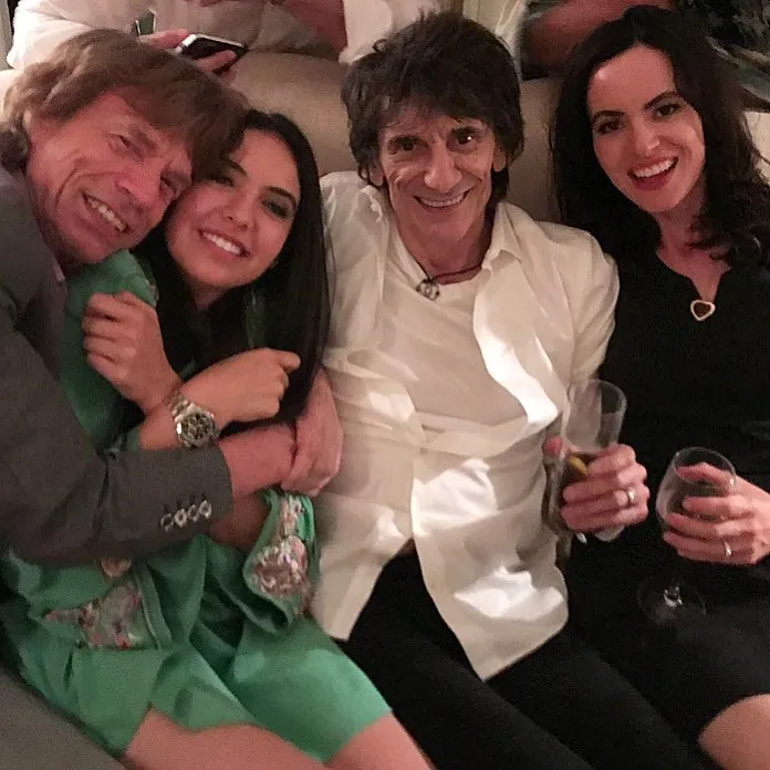 Noor Alfallah smiles with Mick Jagger, Ronnie Wood, and another woman.