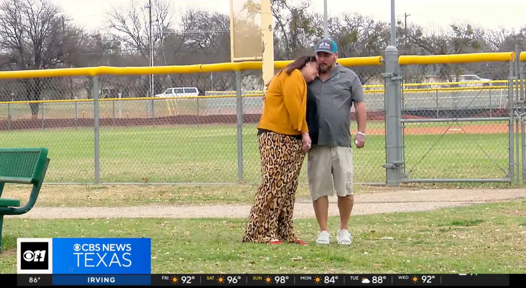 A man and a woman embracing at a baseball field.