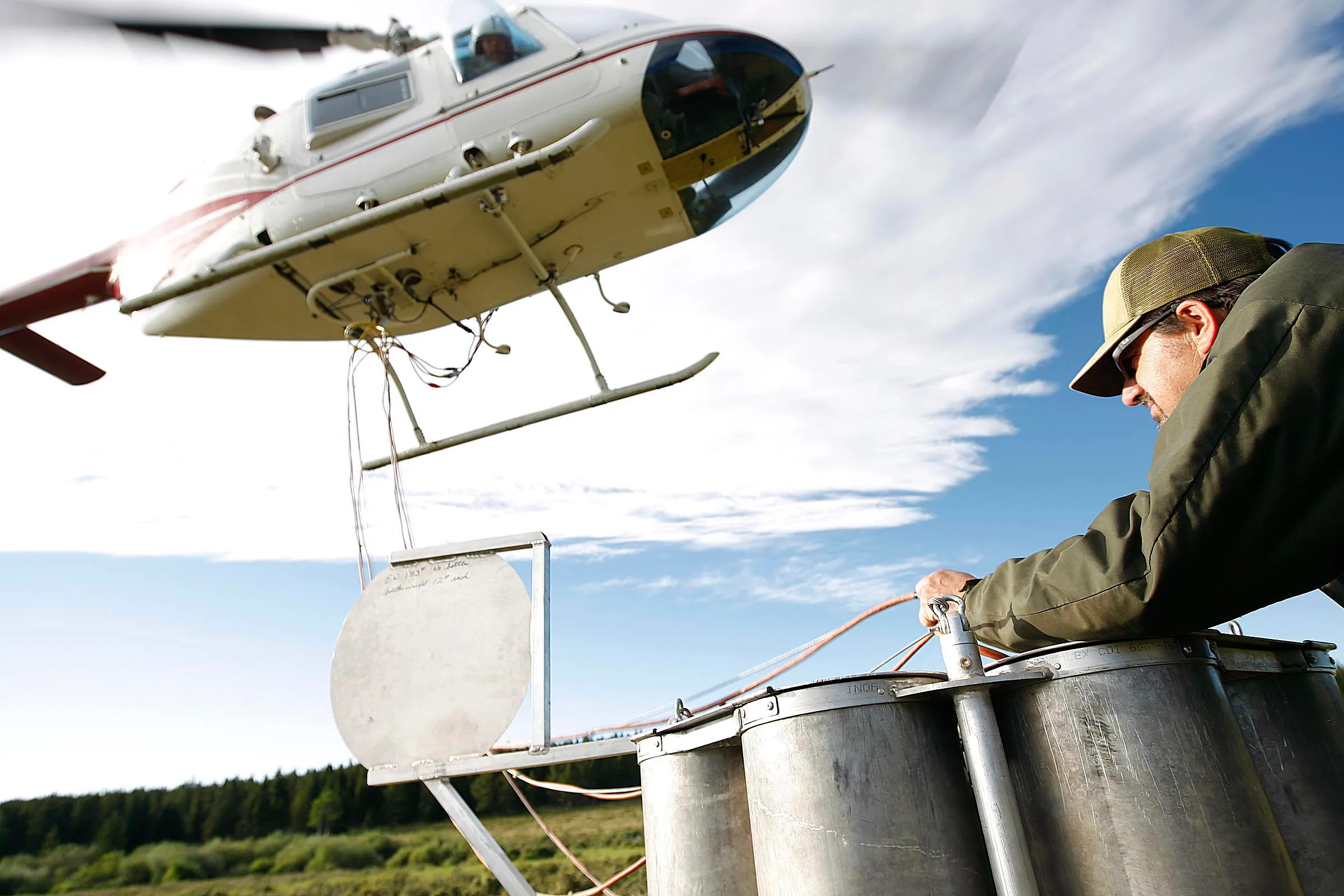 A man holding cords attached to a helicopter to stock mountain lakes A man holding cords attached to a helicopter to stock mountain lakes
