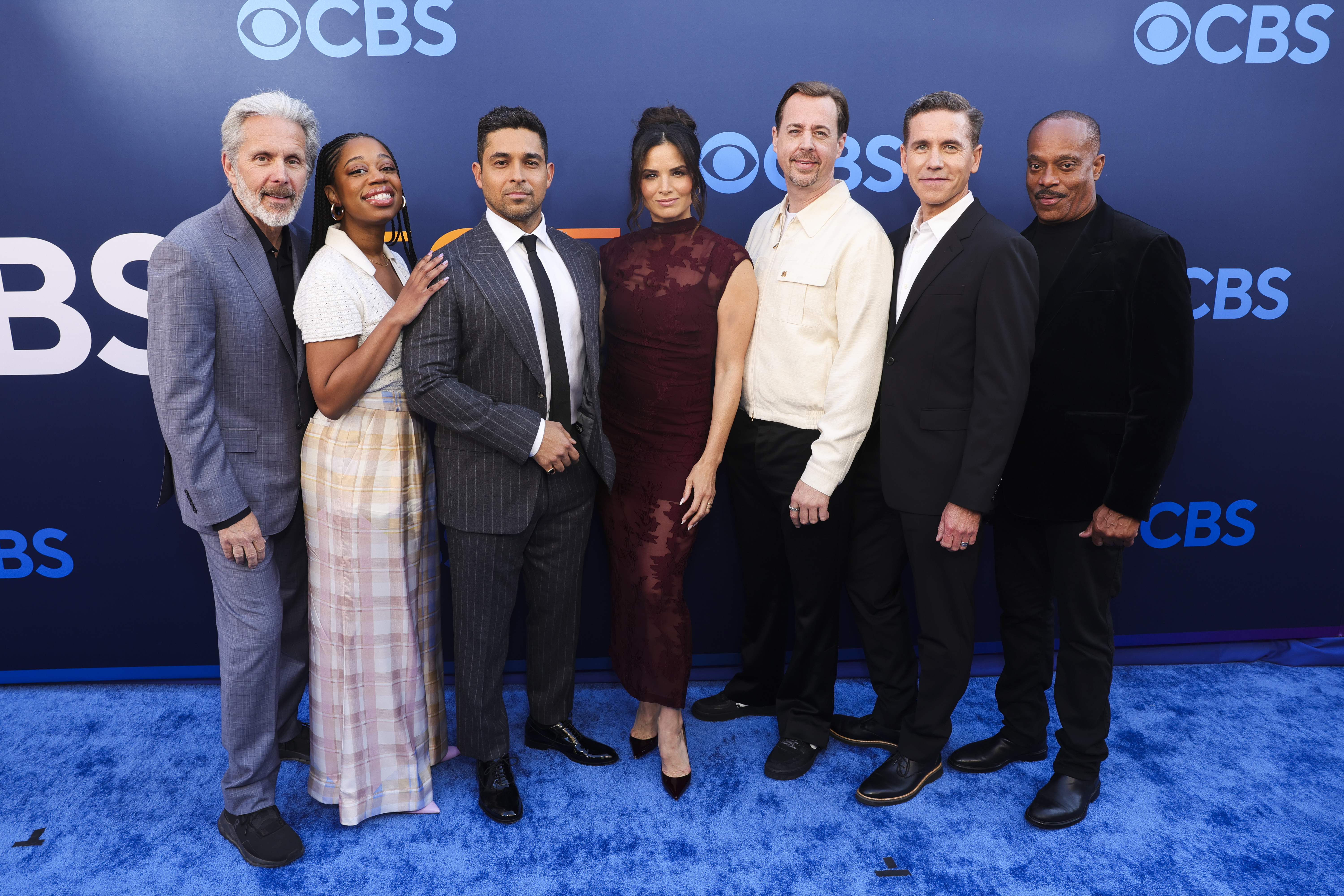 Cast members of NCIS pose on a blue carpet.