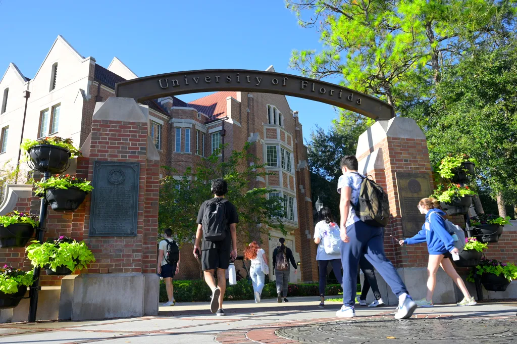 Students walk through the University of Florida archway on a sunny day.