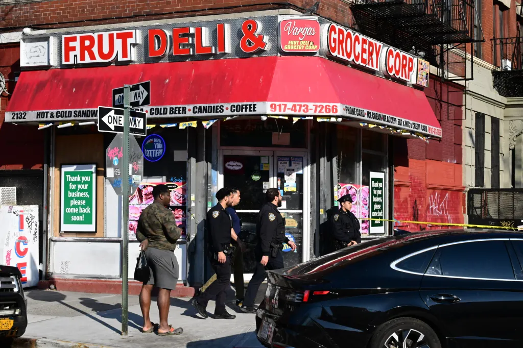 Police officers stand outside Vargas Fruit Deli & Grocery Corp in New York City, where two men were shot.