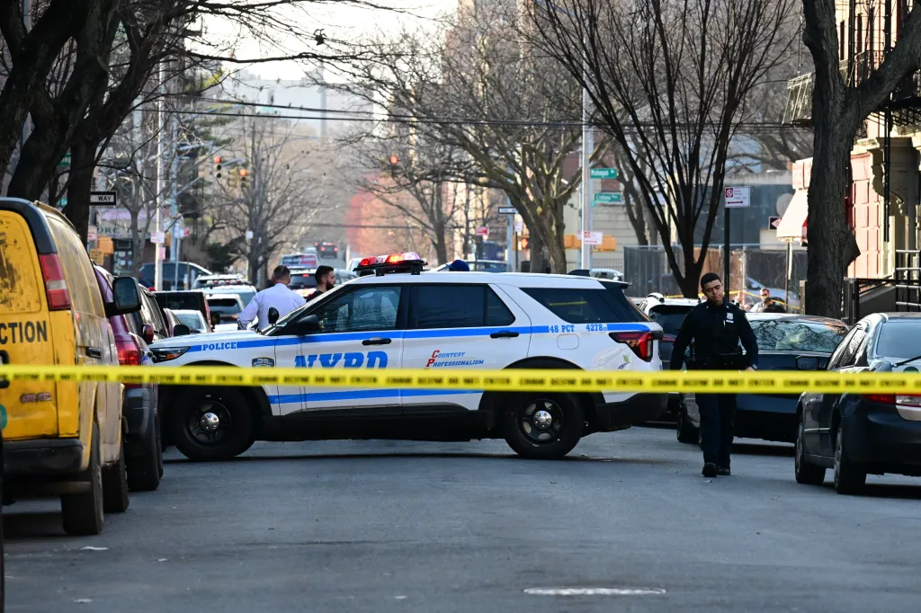 NYPD officers and vehicles behind yellow police tape at 2103 Honeywell Avenue in New York City.