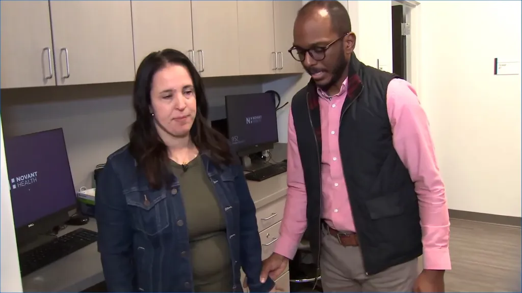 A man and a woman stand next to each other in what appears to be an office.
