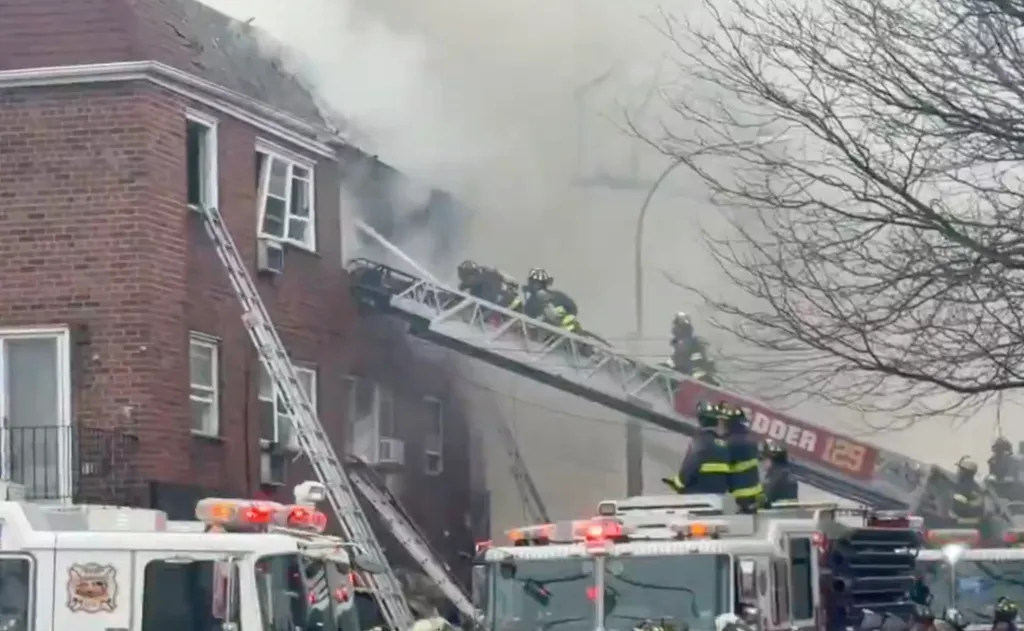 Firefighters on ladders battling a building fire with heavy smoke.