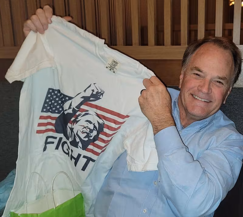 Steve Toth holding a Donald Trump "fight" T-shirt.