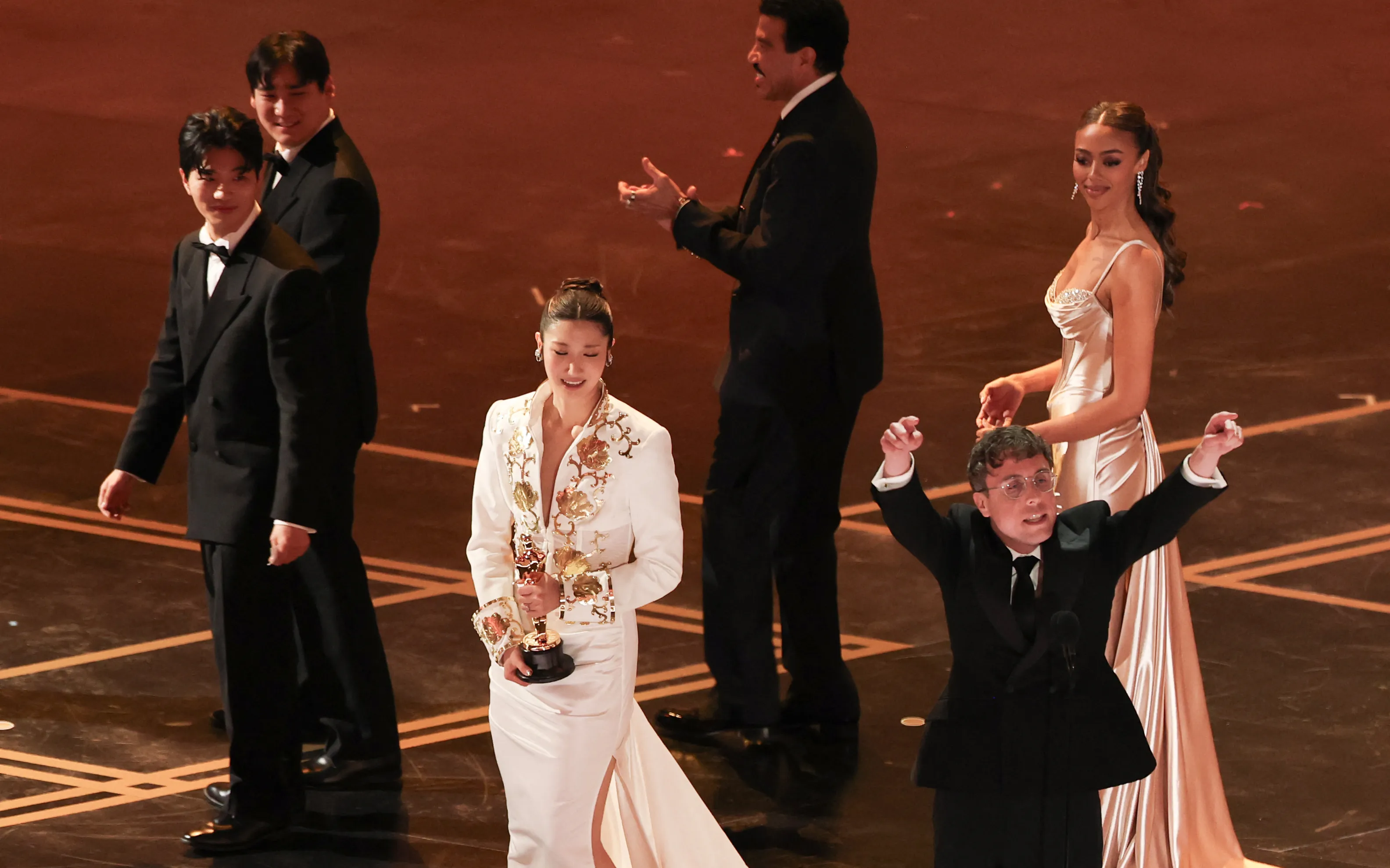 Ejae and Mark Sonnenblick (with his hands up) accepting the award for Best Original Song for
