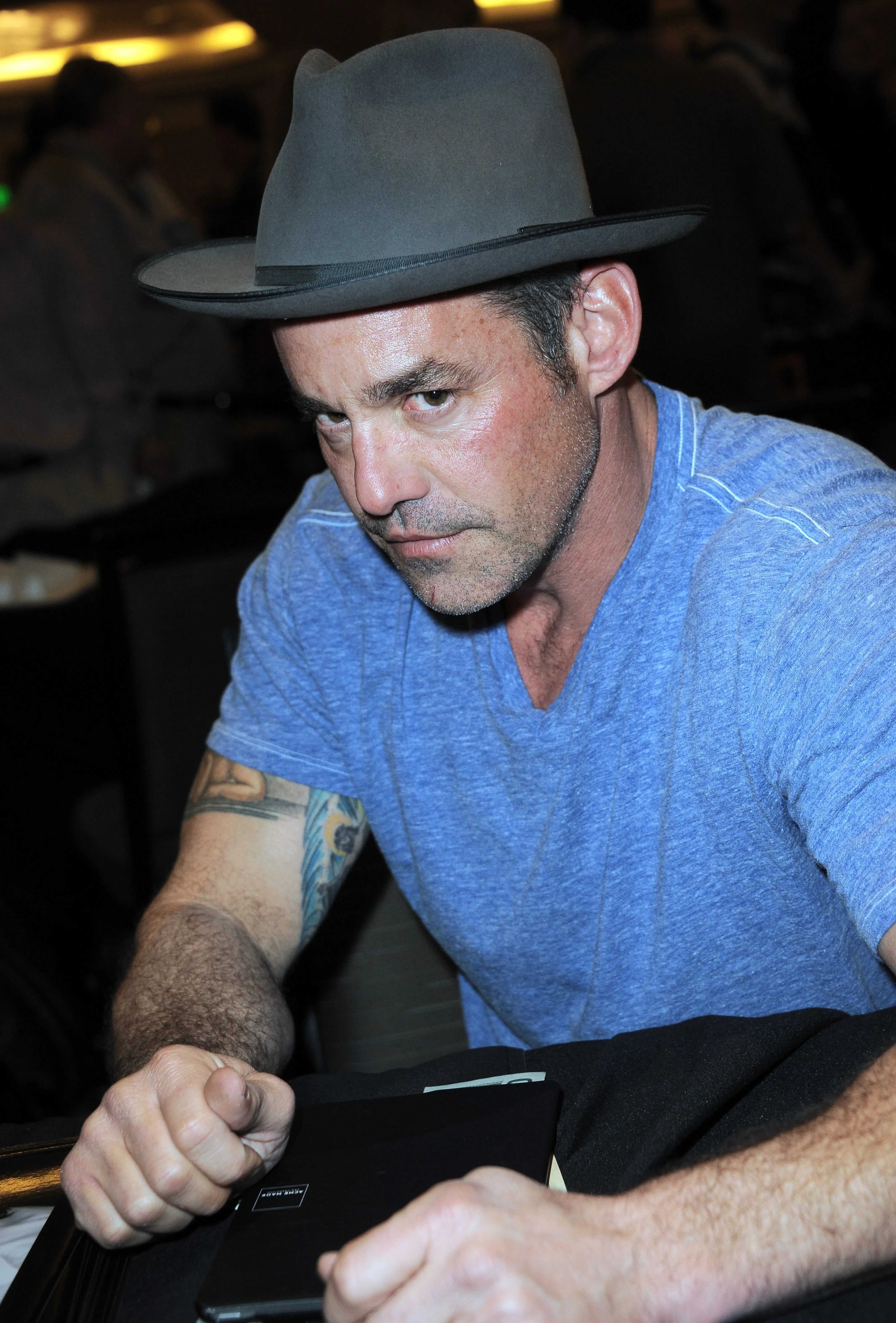 Nicholas Brendon in a fedora hat and blue shirt.