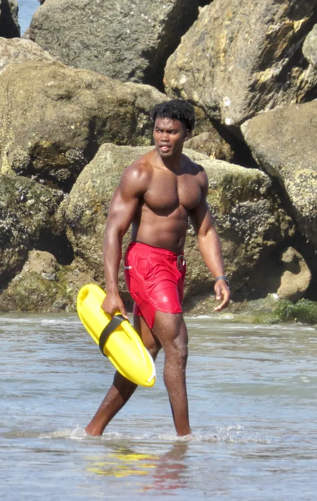 Actor Thaddeus Lagrone at Baywatch Bootcamp, walking through shallow water with a yellow rescue buoy.