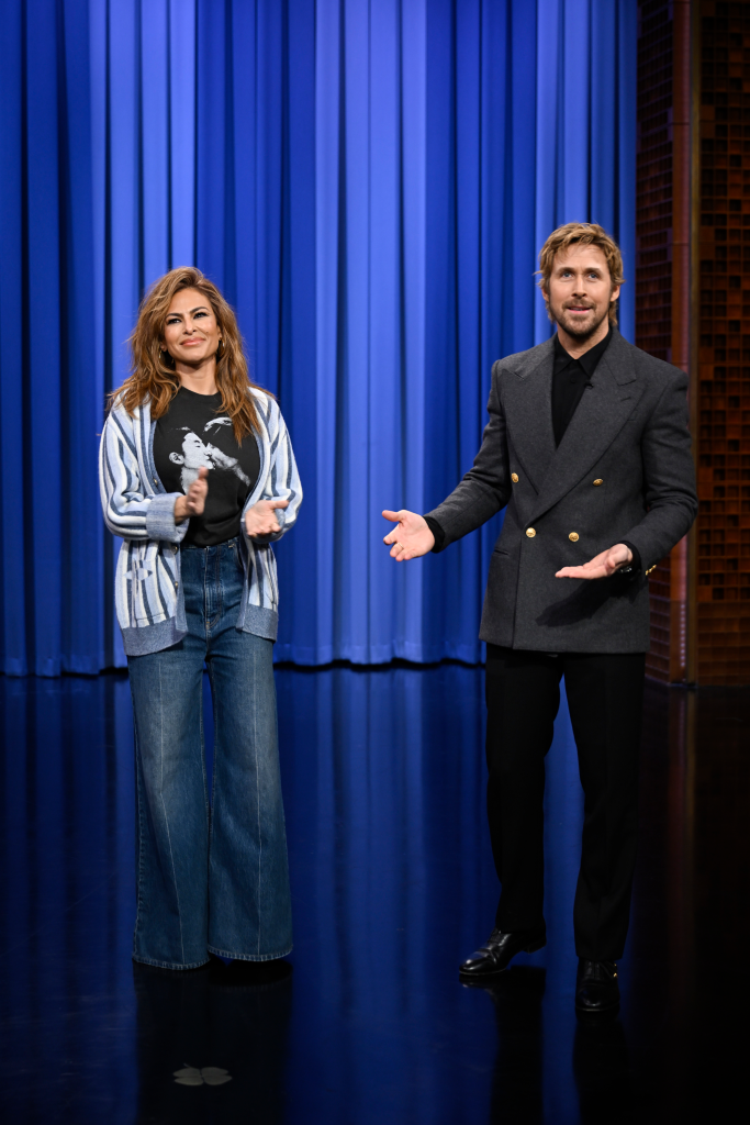 Actress Eva Mendes and actor Ryan Gosling standing on a talk show stage.
