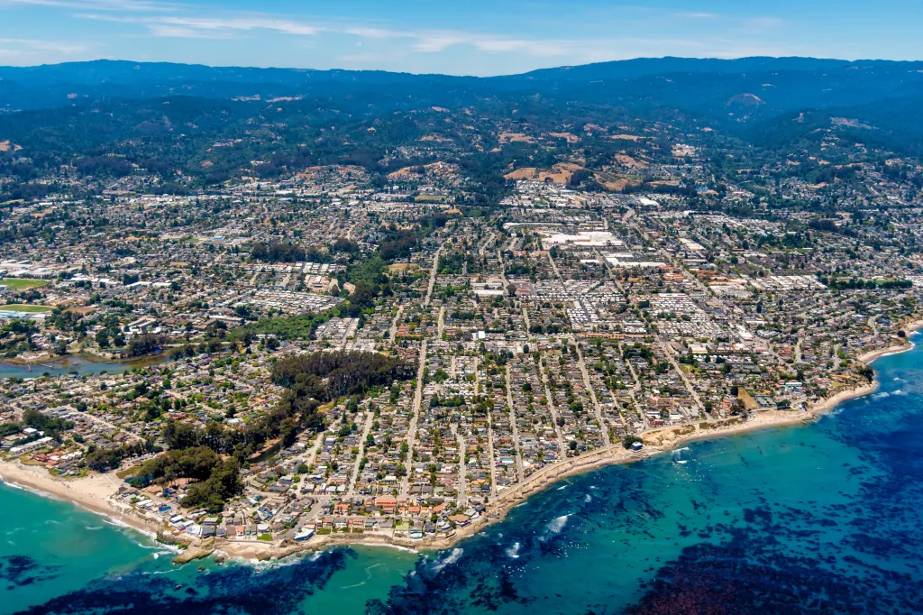 Aerial view of the city of Santa Cruz in Northern California, showing homes, roads, coastline, and the Pacific Ocean.