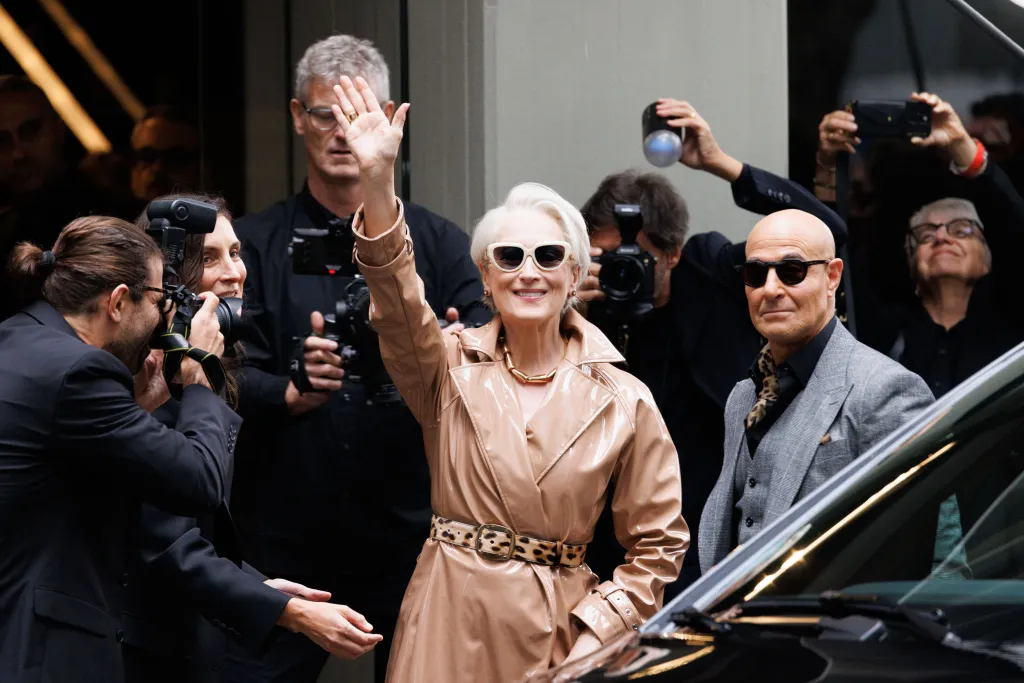 Meryl Streep, in a beige vinyl trench coat and sunglasses, and Stanley Tucci, in a grey suit and sunglasses, arrive at the Dolce & Gabbana fashion show in Milan.