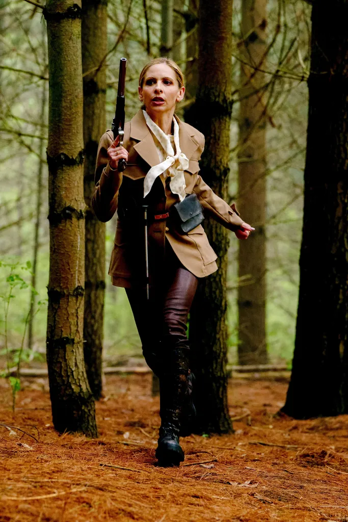 Sarah Michelle Gellar as Daniella in a forest, holding a pistol.
