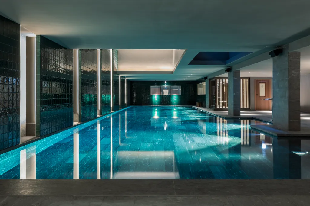 Indoor swimming pool at Hotel La Fondation with blue-green water and dark tiled walls.