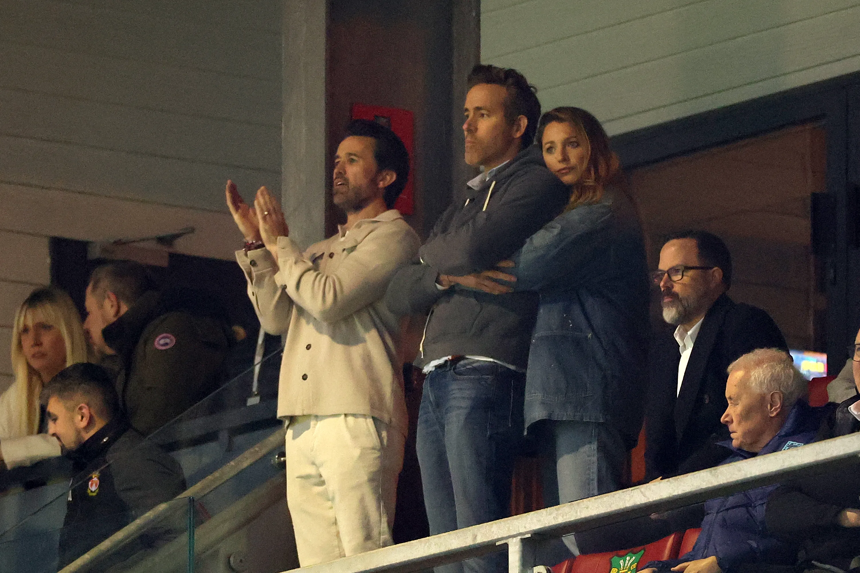 Rob McElhenney applauds while Ryan Reynolds and Blake Lively watch the soccer match.