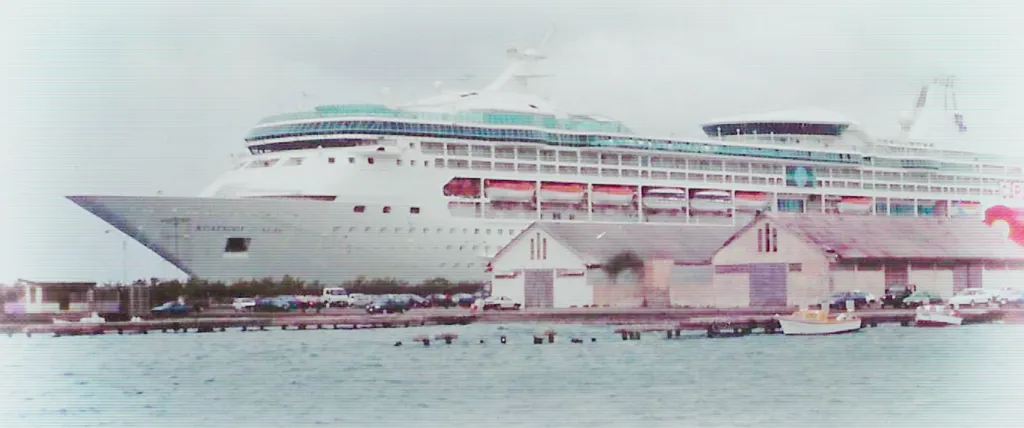 The cruise ship Rhapsody of the Seas docked near a pier with several small buildings.