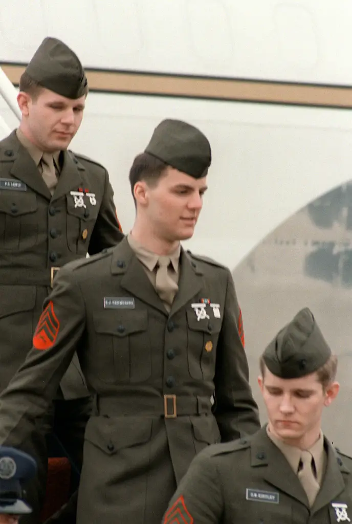 Former Iranian hostages SGT Paul Lewis, SGT Kevin J. Hermening, and SGT Michael E. Moeller in uniform walking down plane steps.